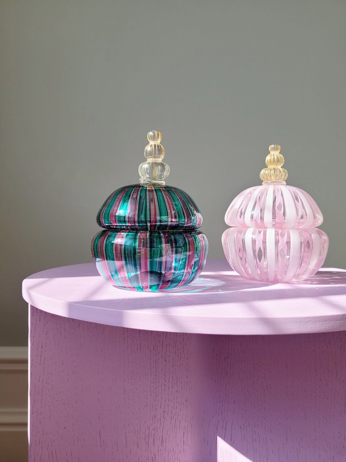 full view of two handcrafted vintage striped Murano bonbonnieres on a purple side table