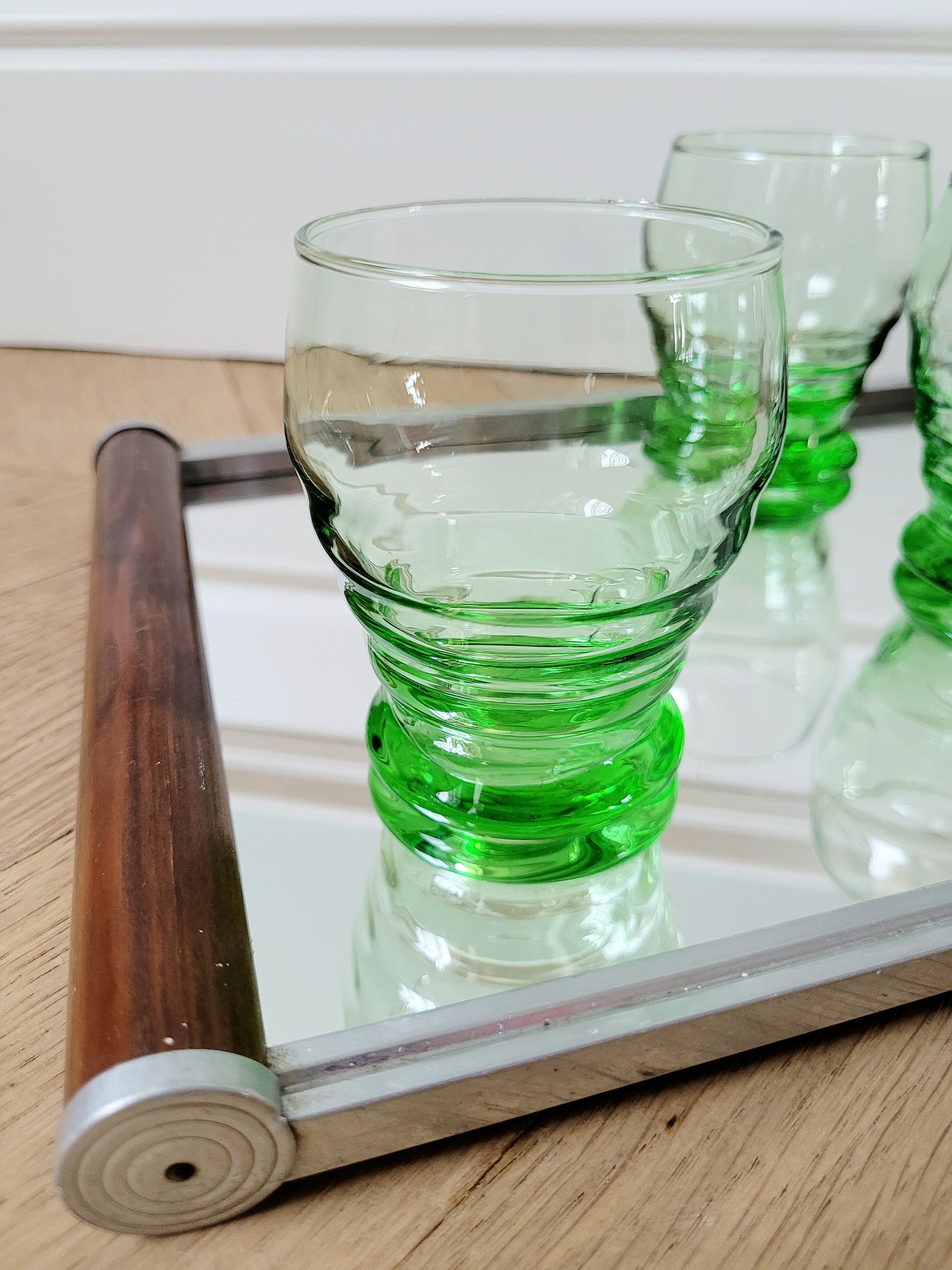 detail of bright green art deco drinking glasses on a mirror tray