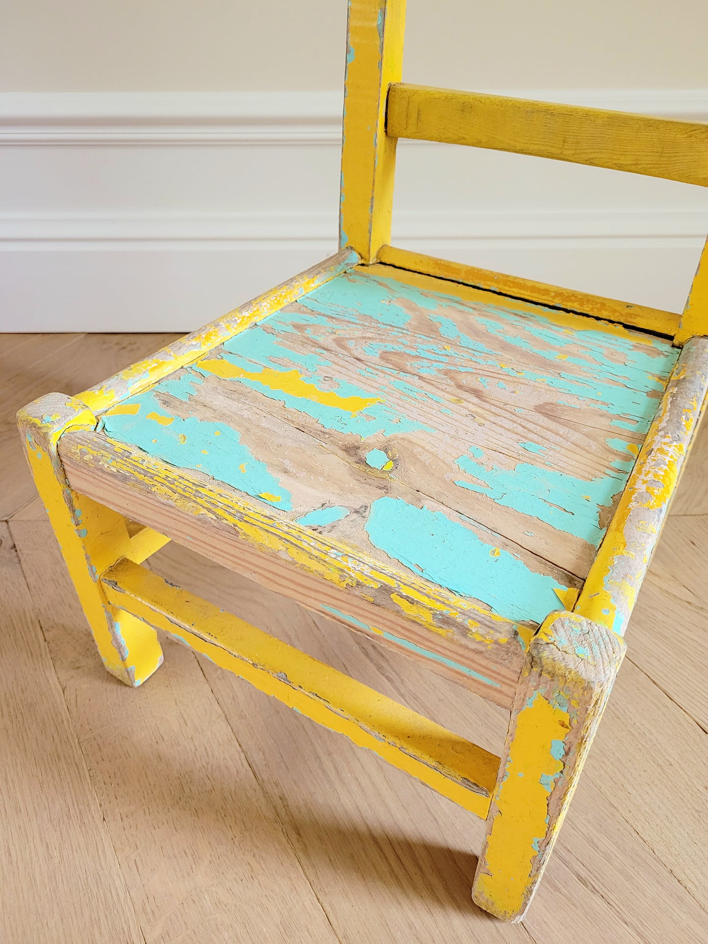 detail of a characterful wooden kids chair in yellow and green with patina