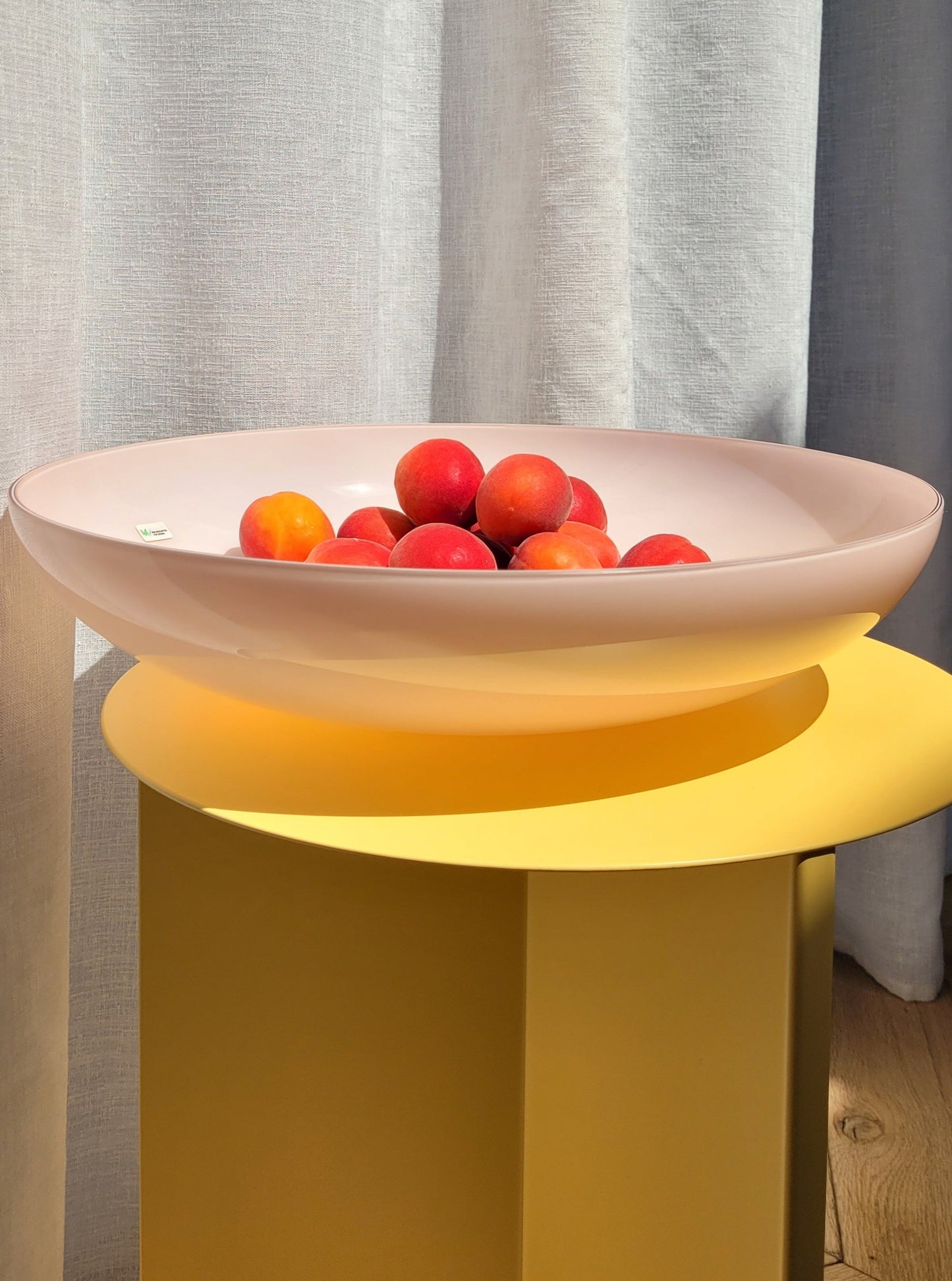 front view of a large vintage opal pink Murano bowl on a yellow side table
