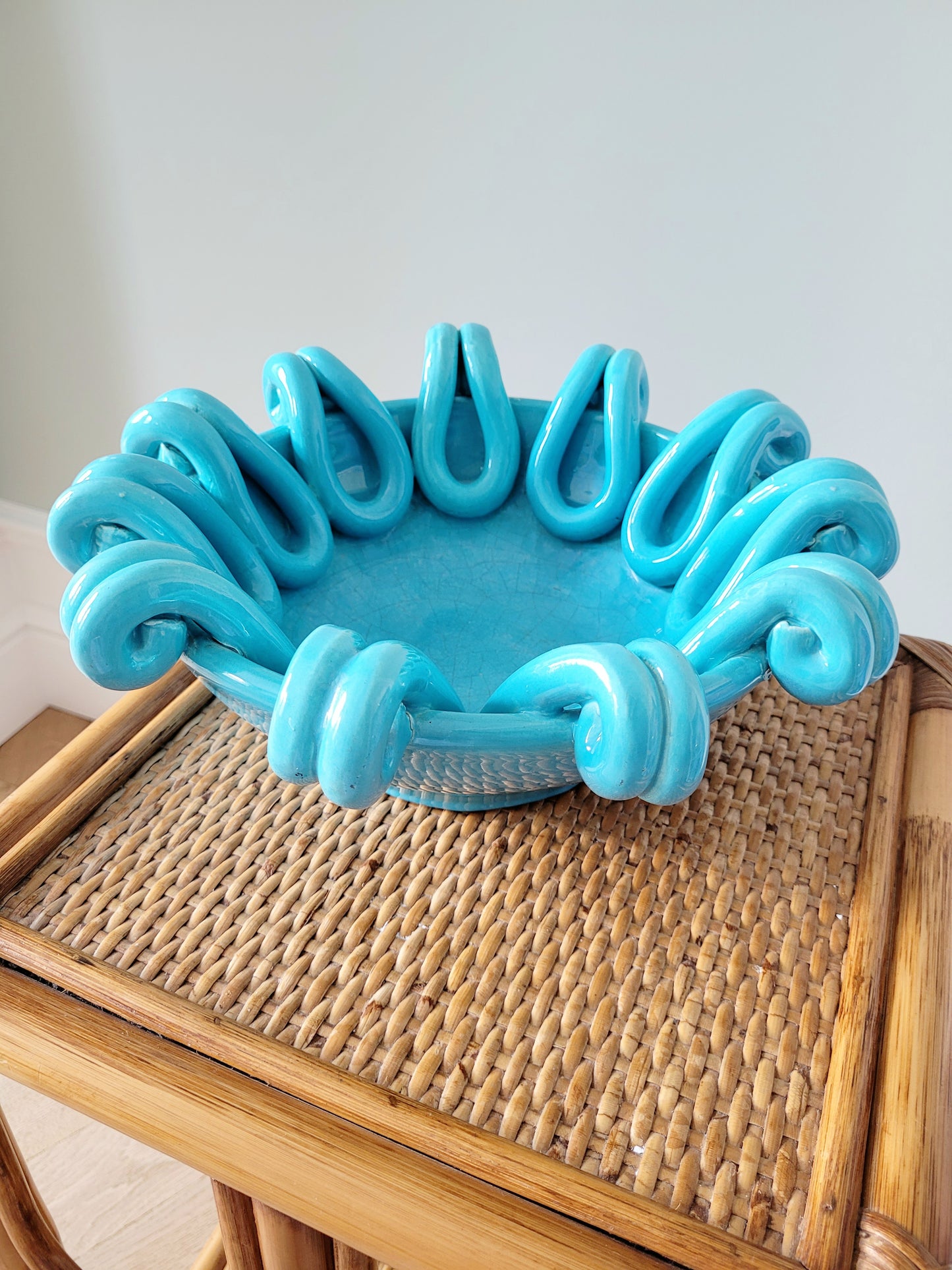 side view of a striking turquoise ceramic serving bowl on a bamboo side table