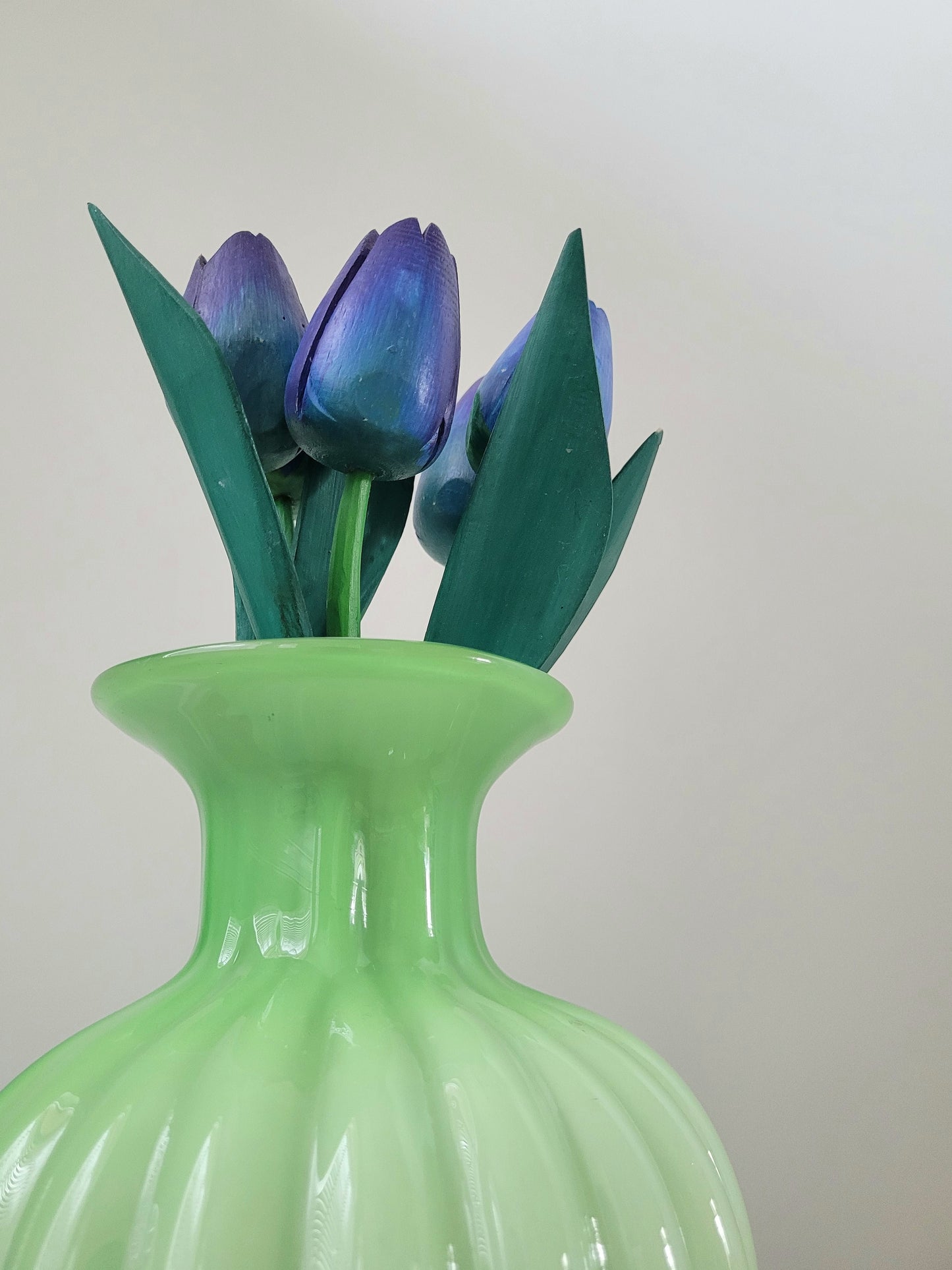 detail of a vibrant green glass vase with wooden tulips