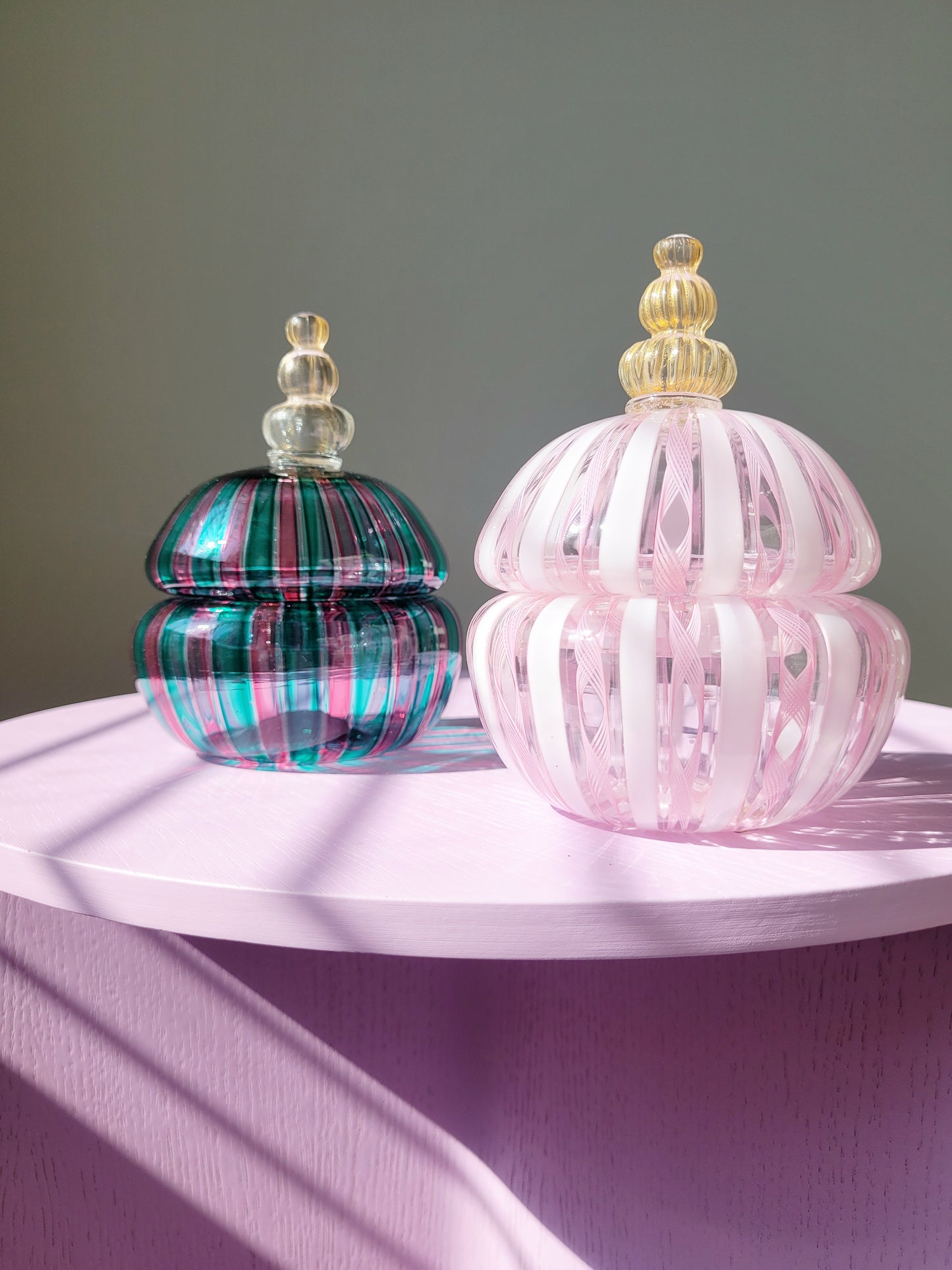 front view of two handcrafted vintage striped Murano bonbonnieres on a purple side table