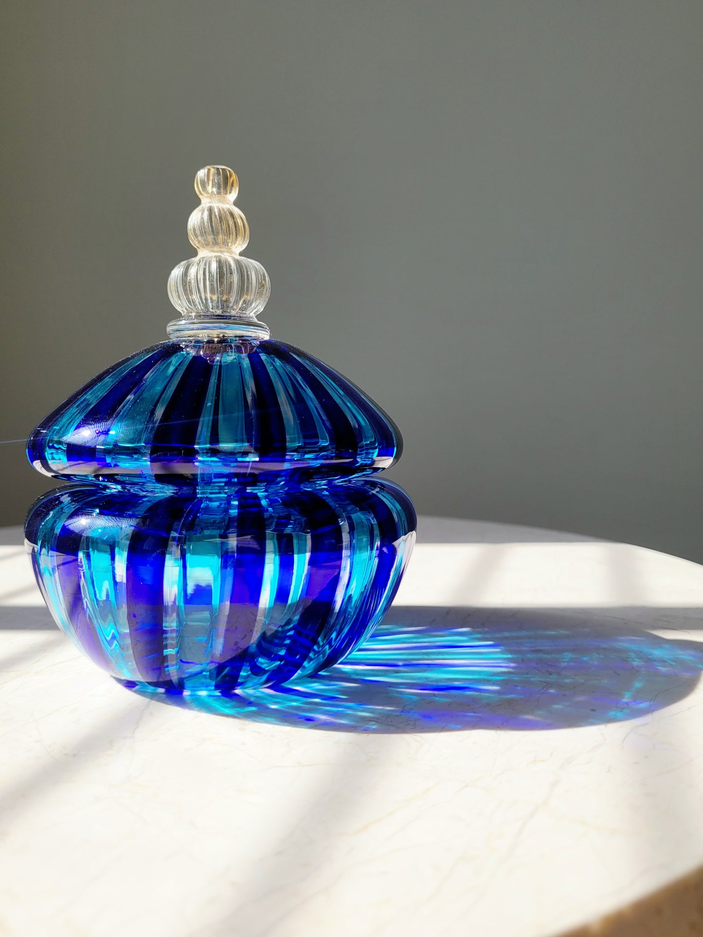 front view of a handcrafted vintage striped Murano bonbonniere in blue and gold