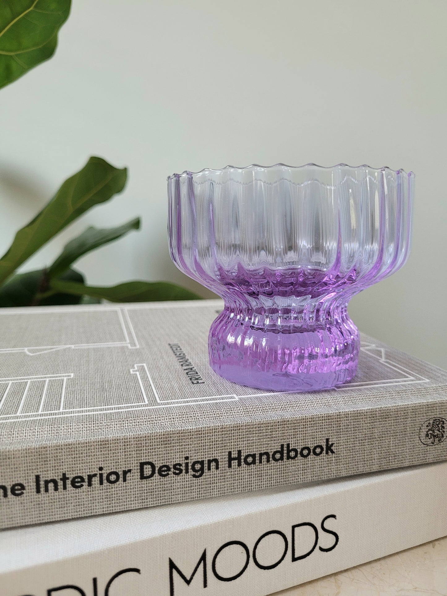 detail of a purple Italian glass and cup on a stack of interior books