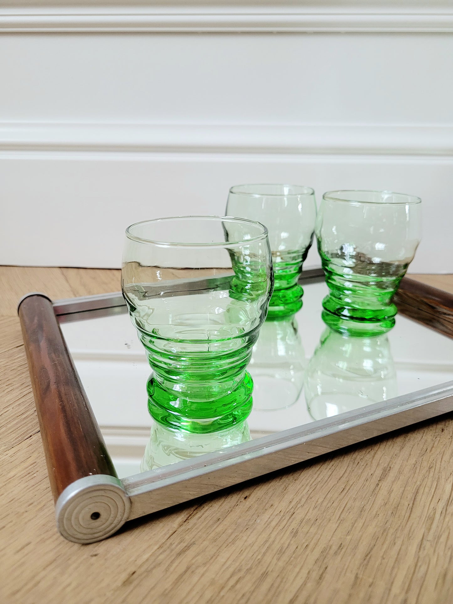 front view of bright green art deco drinking glasses on a mirror tray