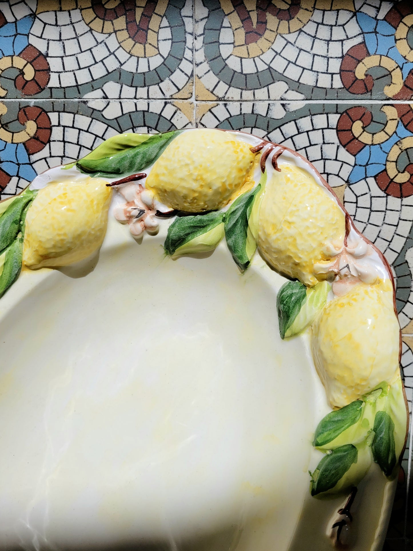 detail of a deep ceramic oval dish with lemons in relief