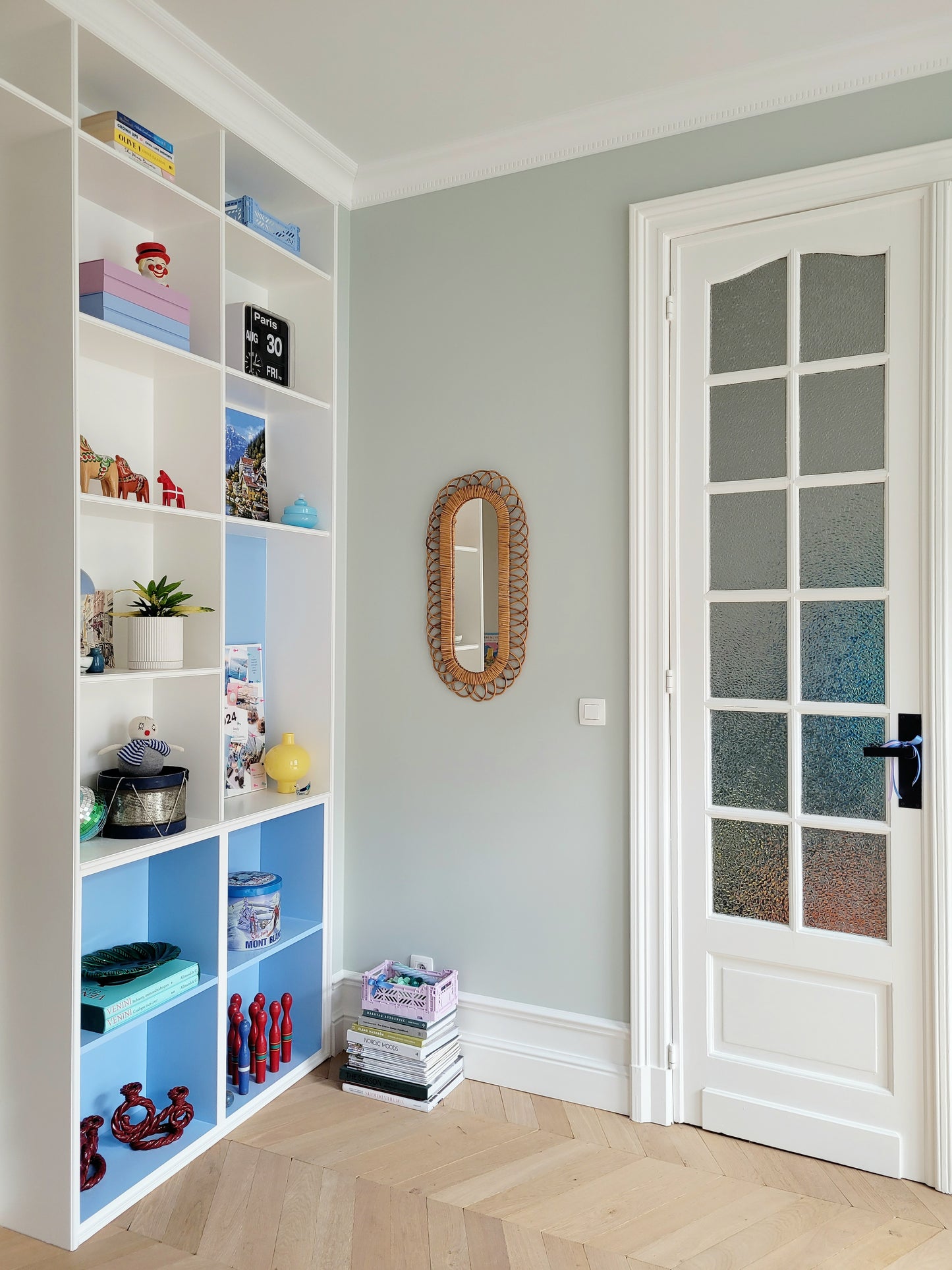 full view of an elongated vintage rattan wall mirror possibly from Franco Albini with filled cabinets on the side