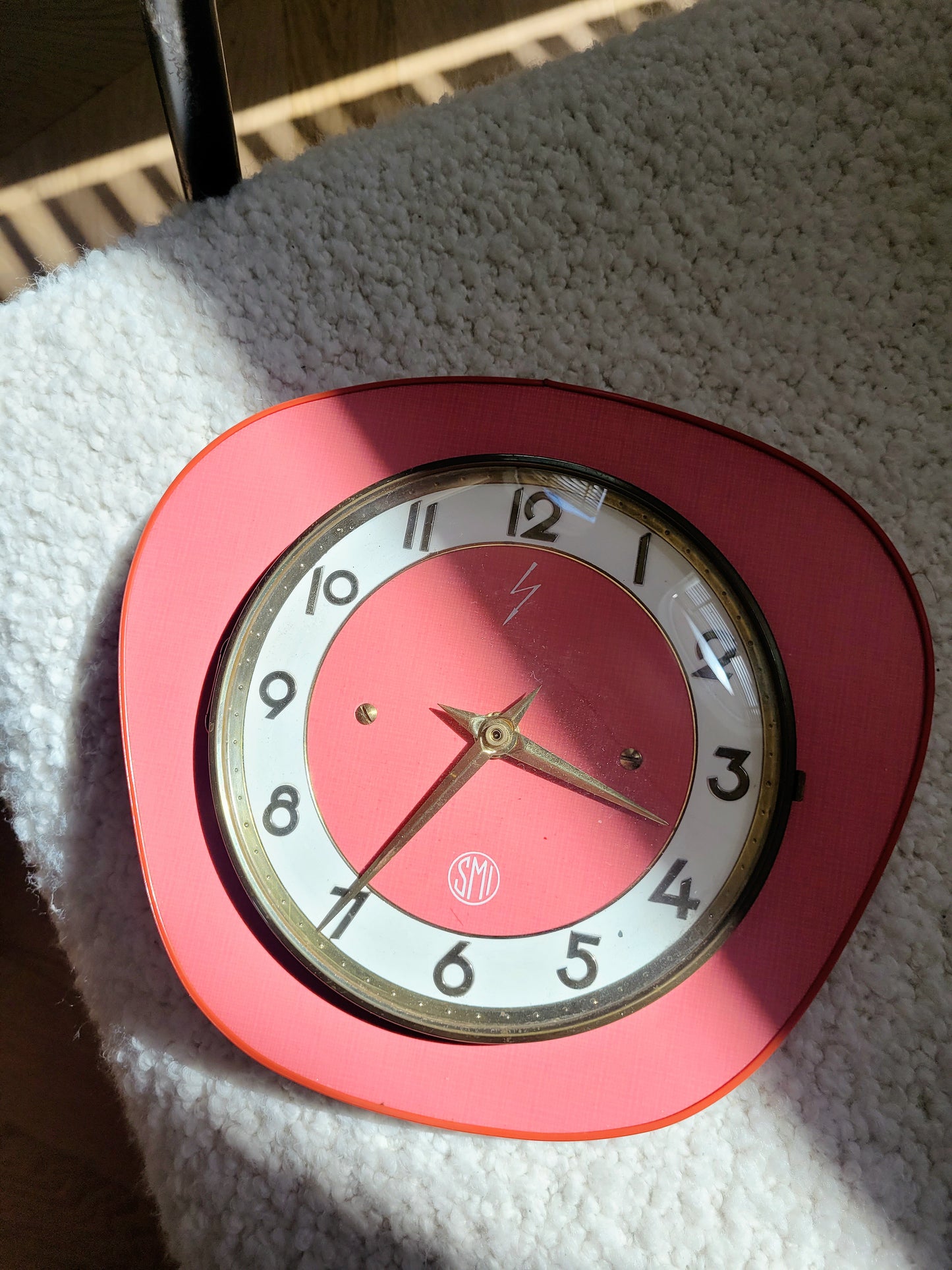 top view of a red wall clock of the French brand SMI in formica with a brass ring and curved glass