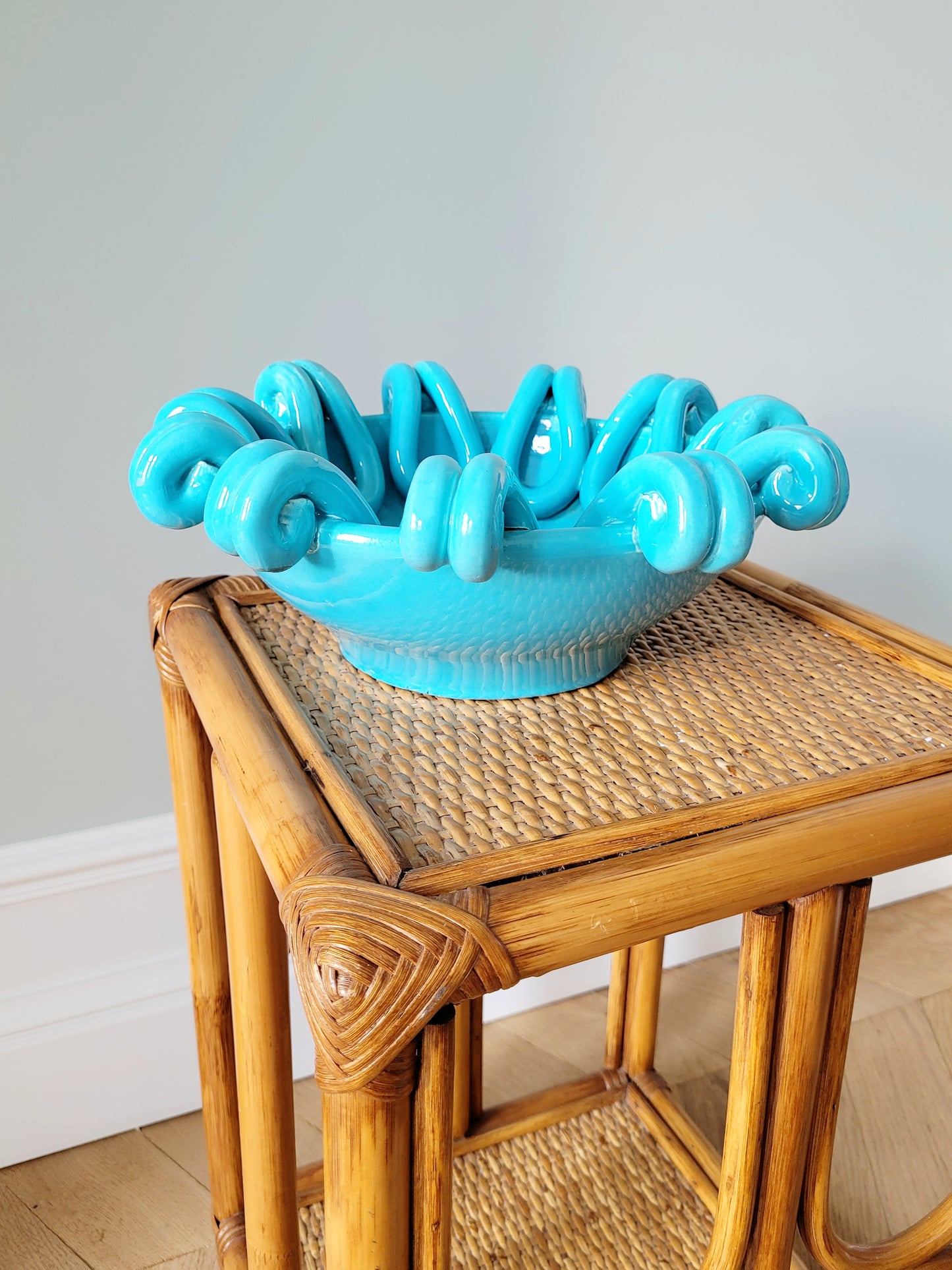 side view of a striking turquoise ceramic serving bowl on a bamboo side table