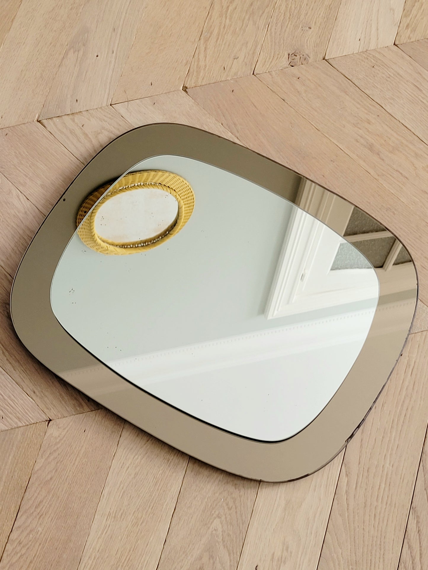 top view of a vintage two-tone Italian wall mirror with smoked glass