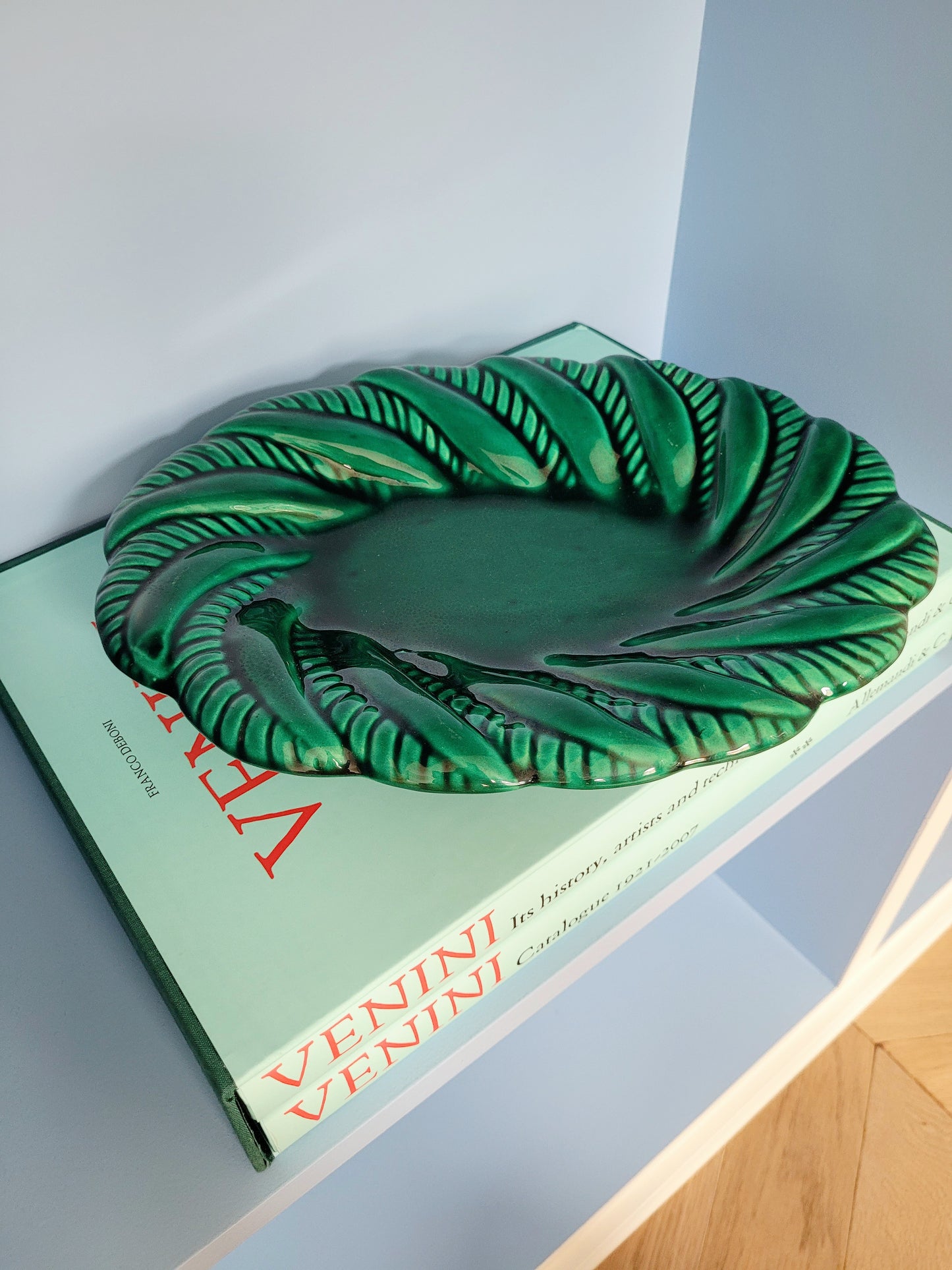 top view of a vintage green ceramic plate on a shelf
