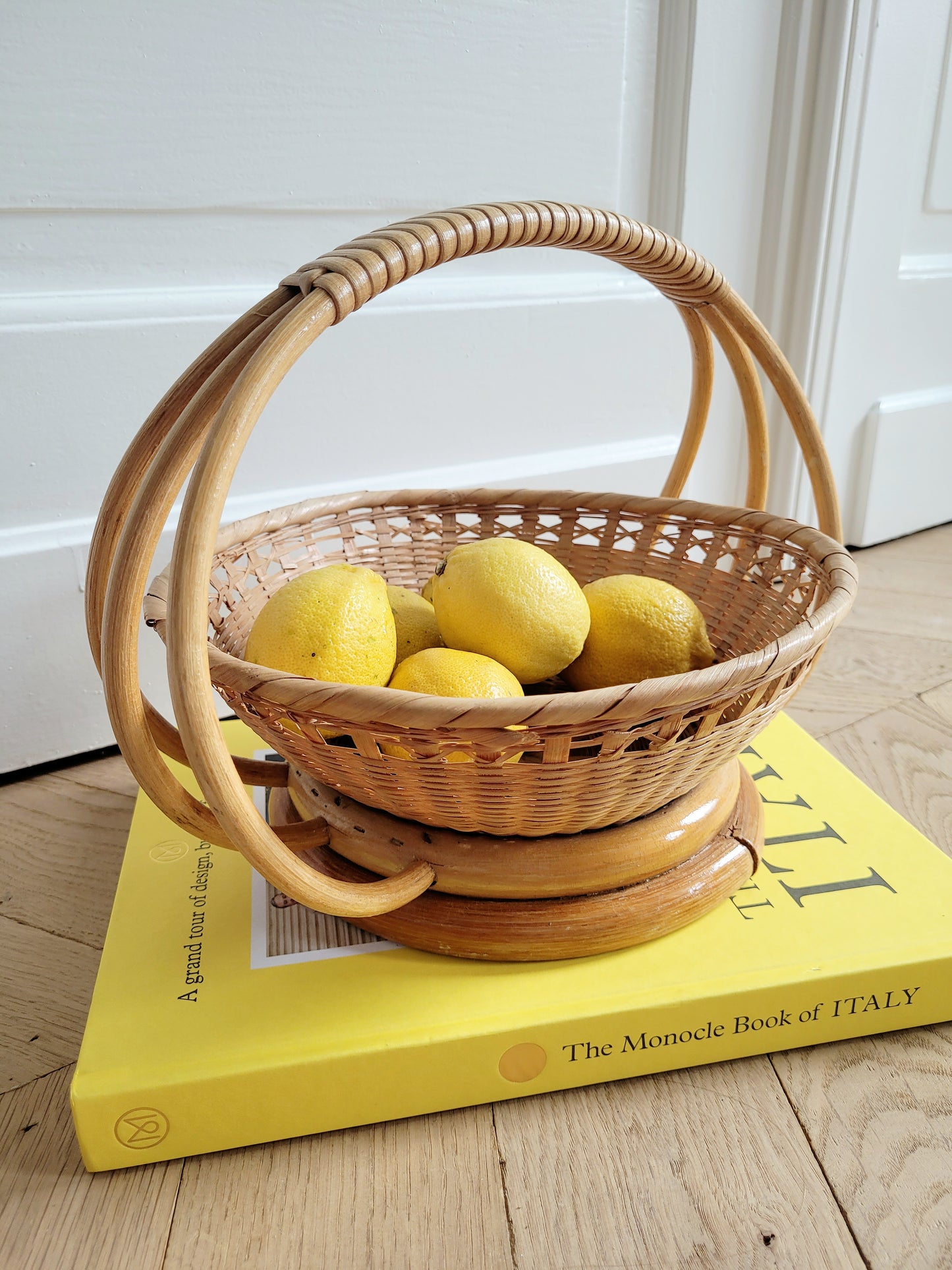 side view of a wicker and rattan fruit basket filled with lemons