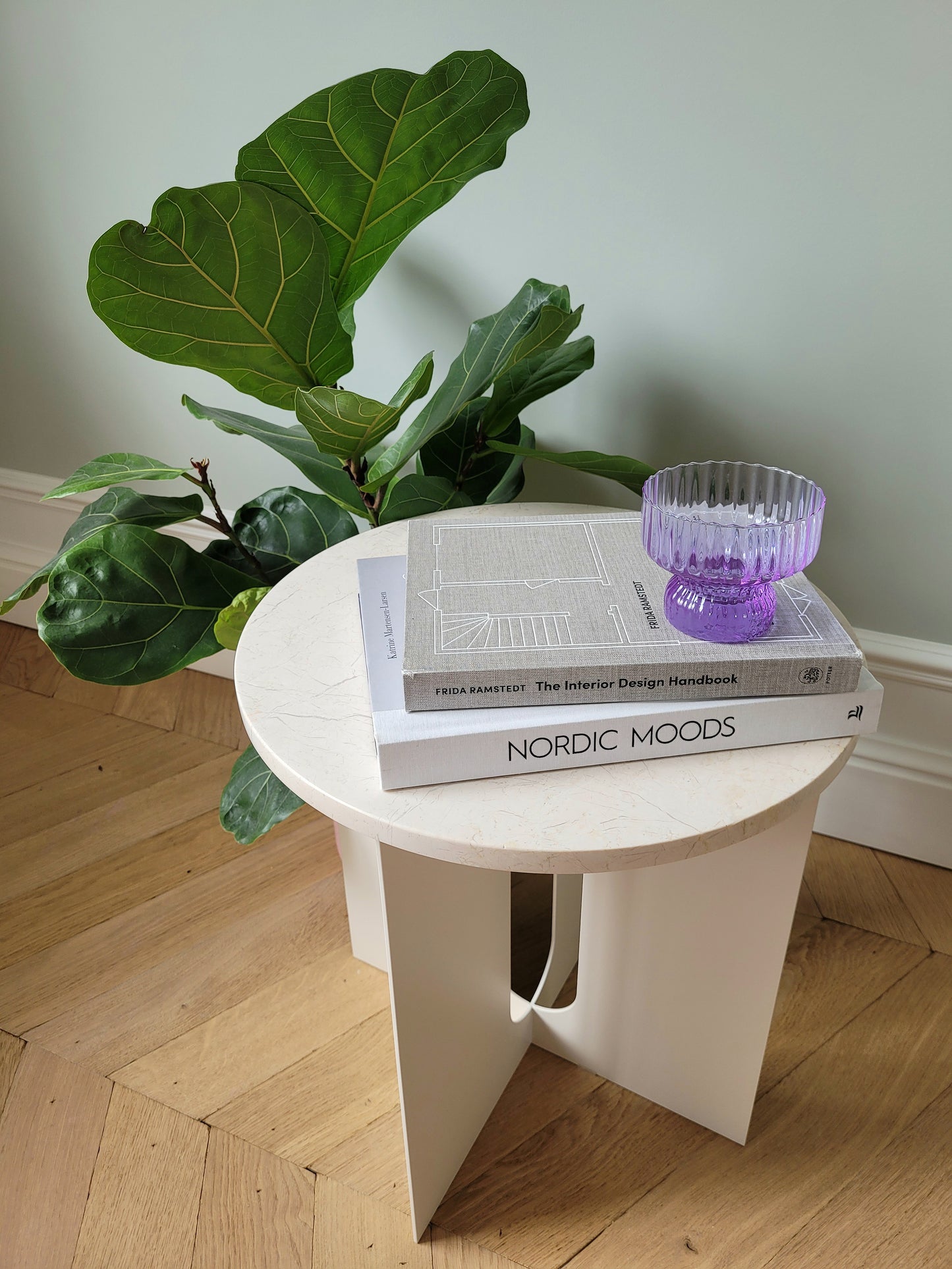 full view of a purple Italian glass and cup on a stack of interior books and marble side table