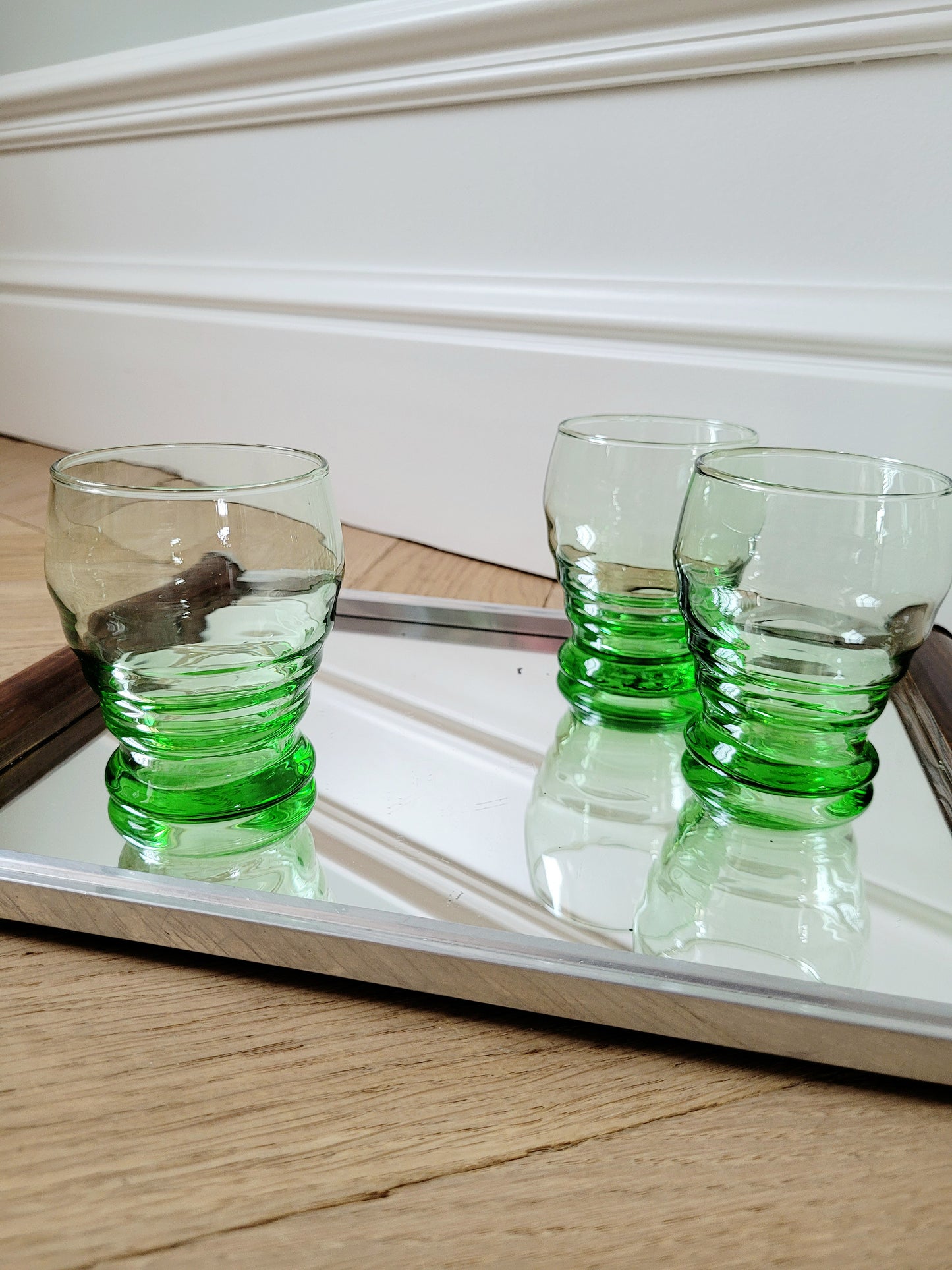 side view of bright green art deco drinking glasses on a mirror tray