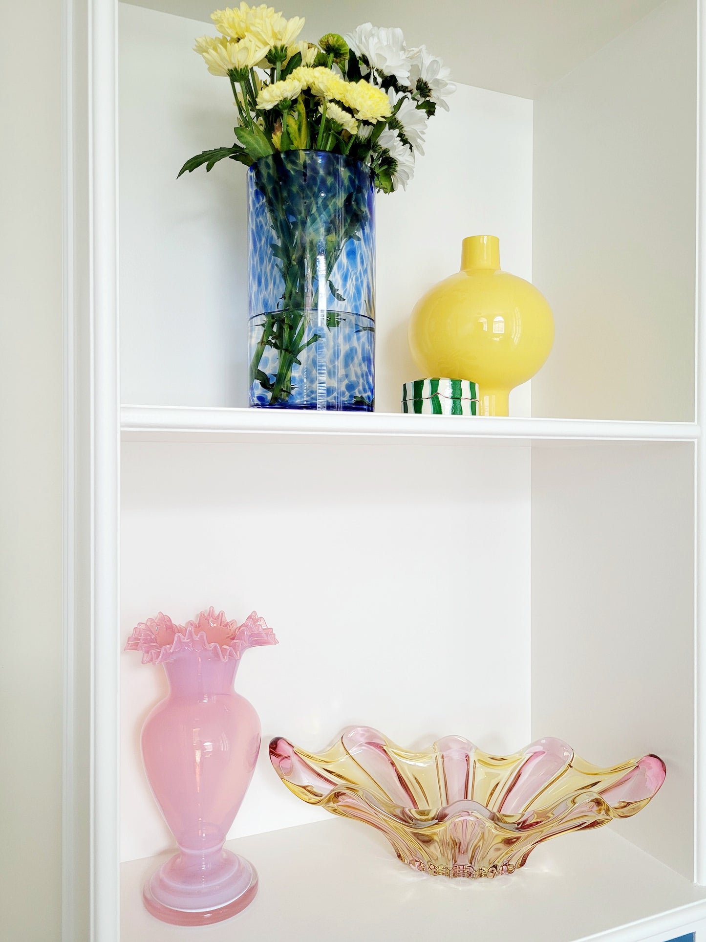 full view of a vibrant candy coloured glass serving or trinket bowl in yellow and pink on white shelves