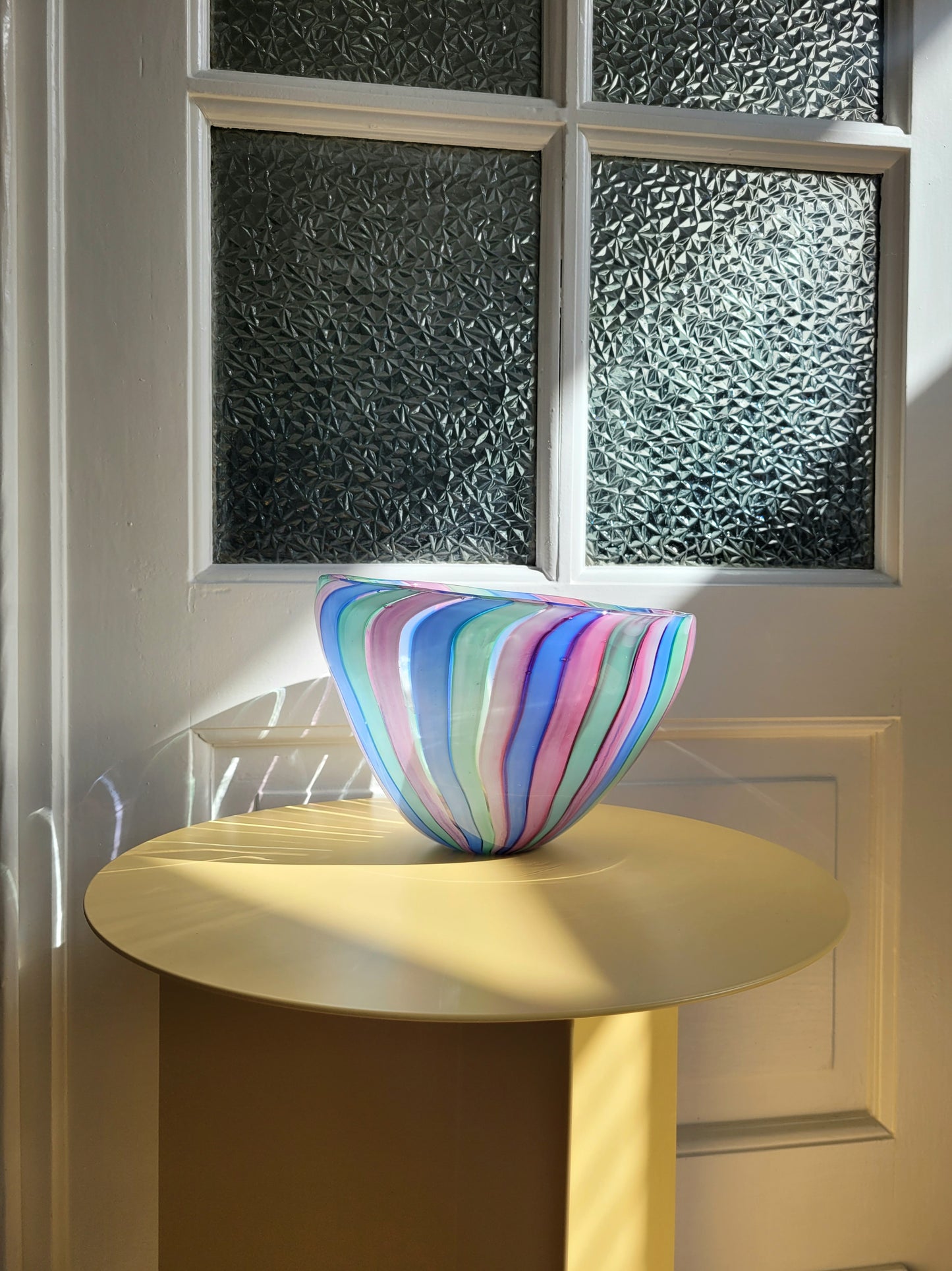 full view of a vintage candy stripe Murano bowl on a yellow side table