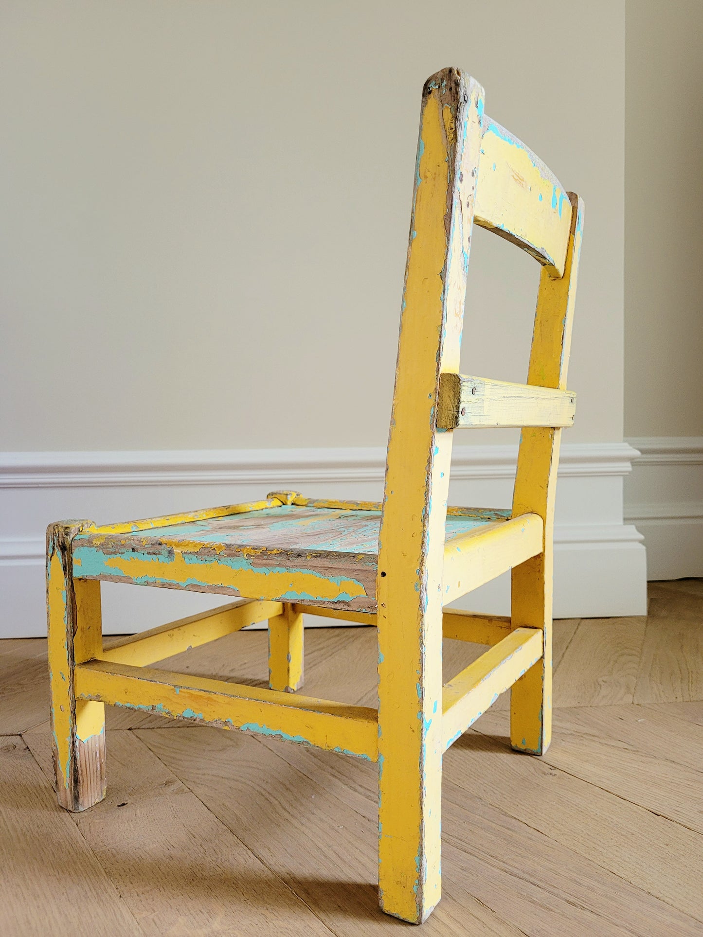 side view of a characterful wooden kids chair in yellow and green with patina