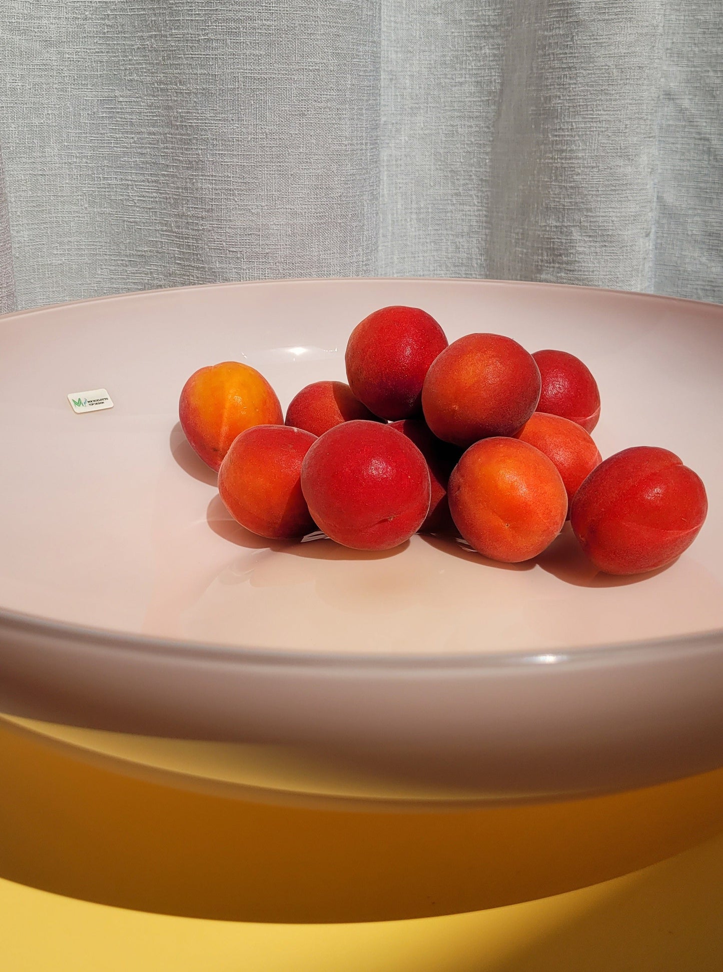 detail of a large vintage opal pink Murano bowl filled with fruit on a yellow side table