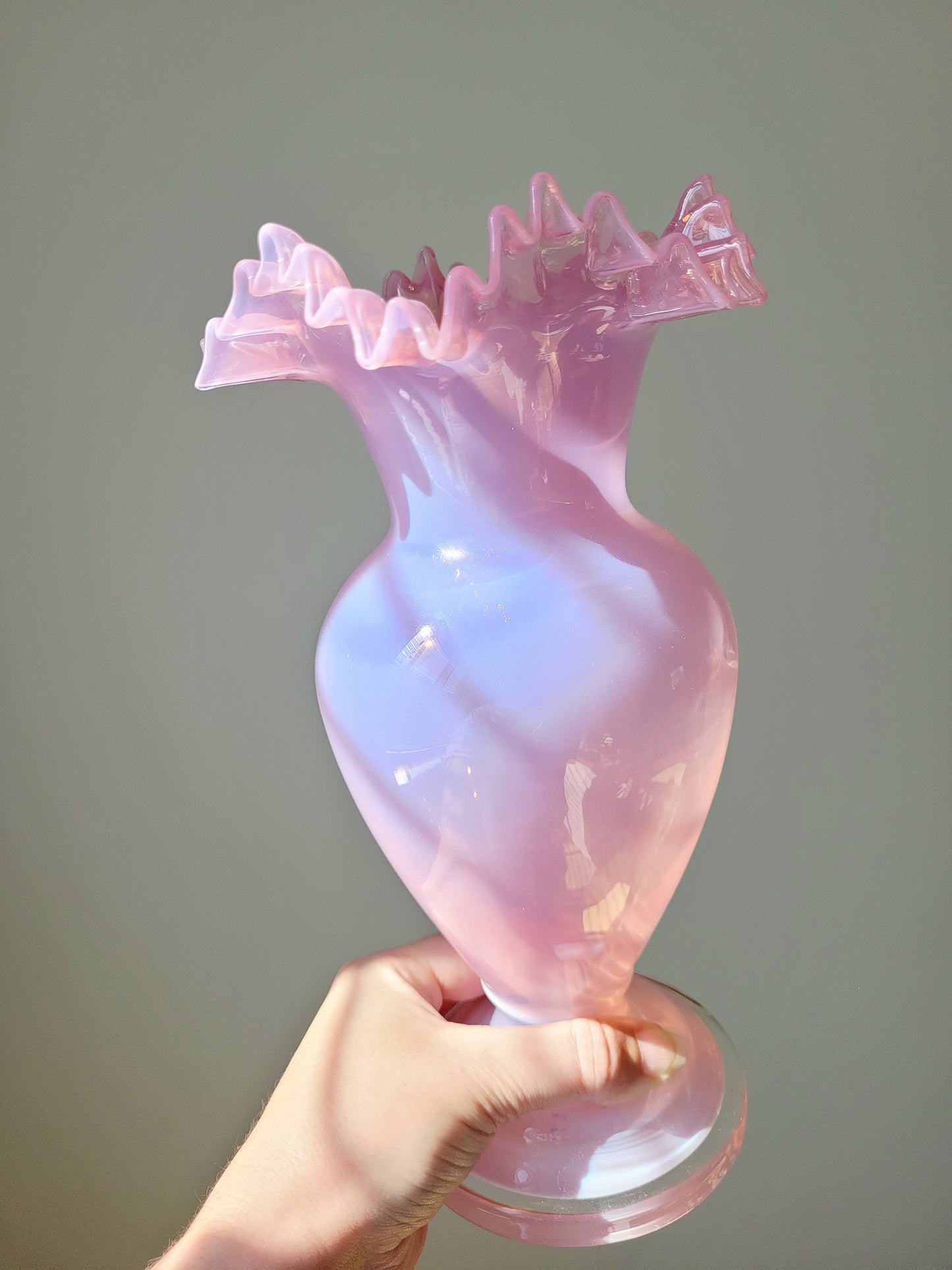 full view of a tilted pink opaline glass vase handheld