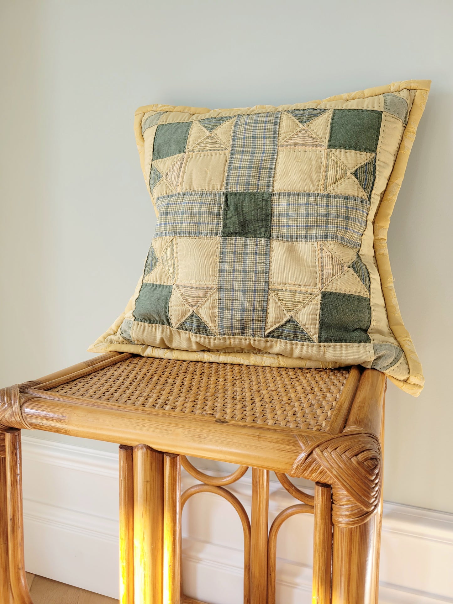 front view of quilted cushion in green and yellow hues and pattern