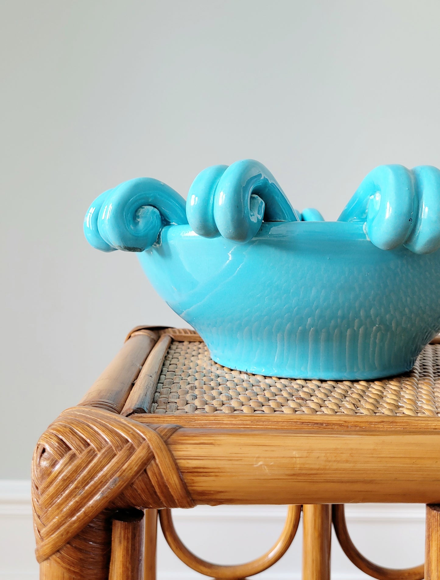 detail of a striking turquoise ceramic serving bowl on a bamboo side table