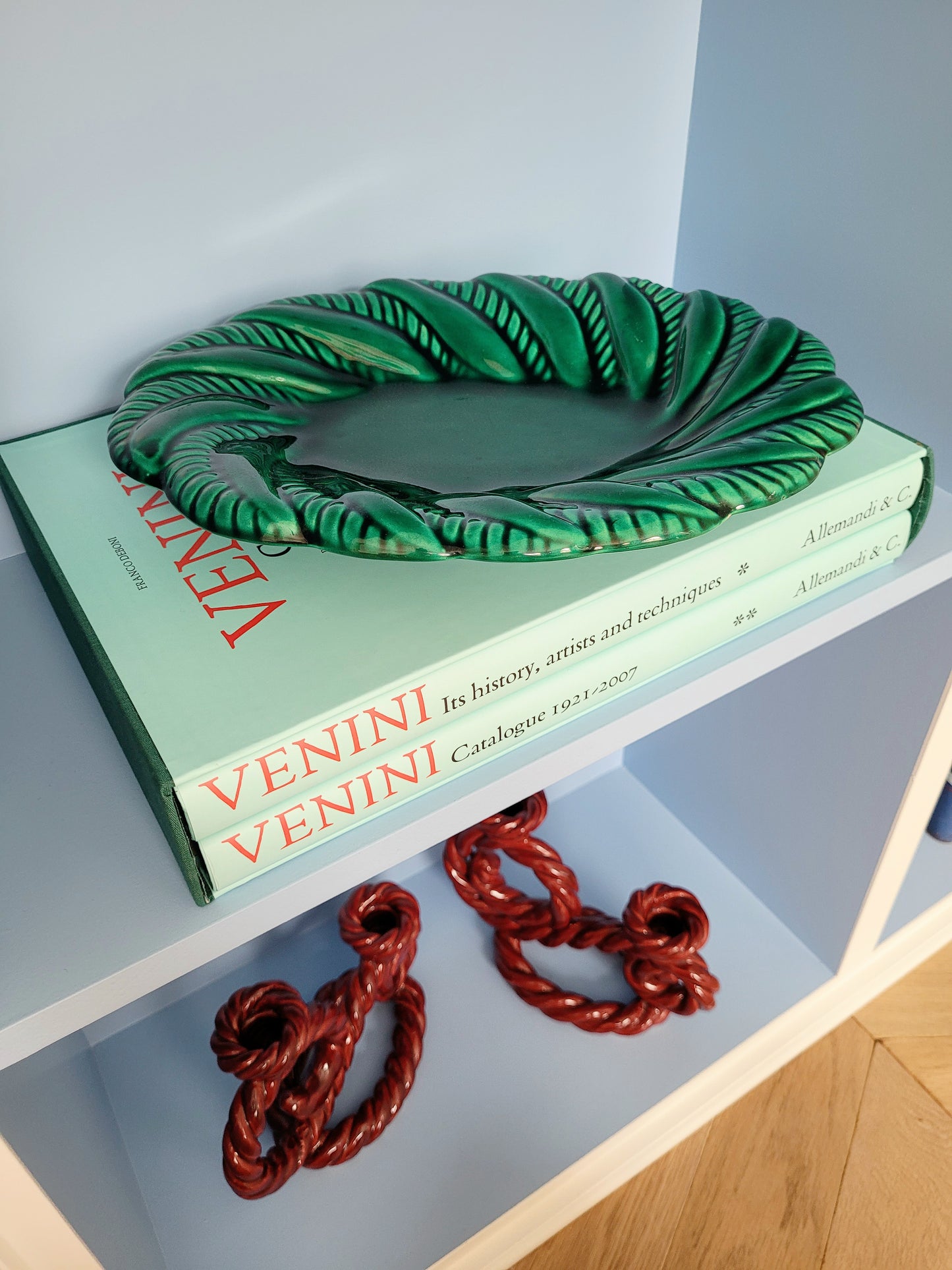 top view of a vintage green ceramic plate on a blue shelf