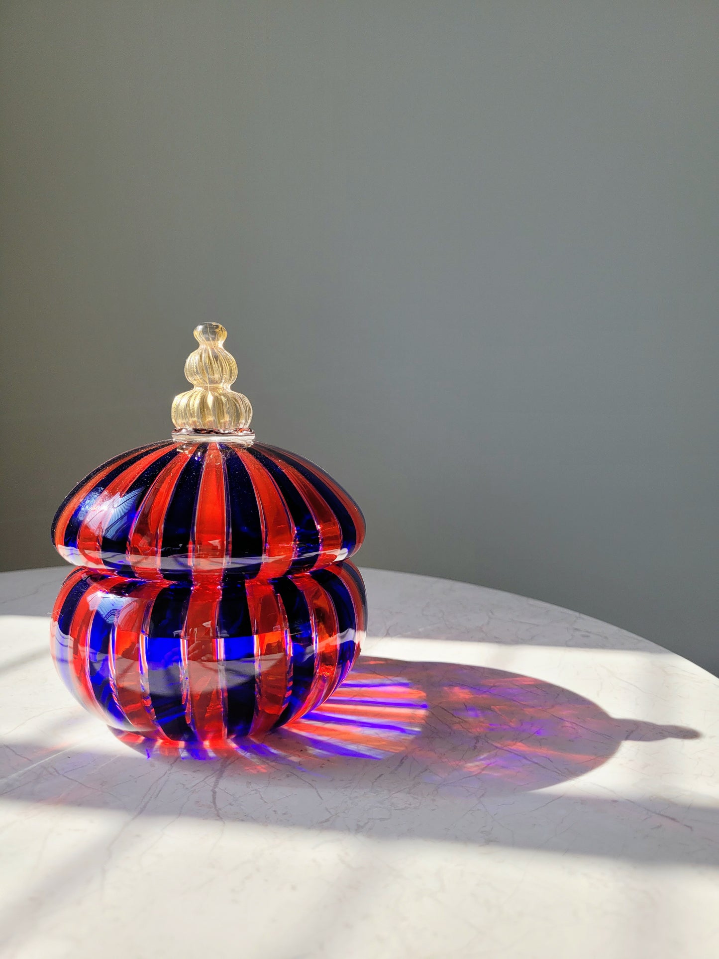 front view of a handcrafted vintage striped Murano bonbonniere in red blue and gold