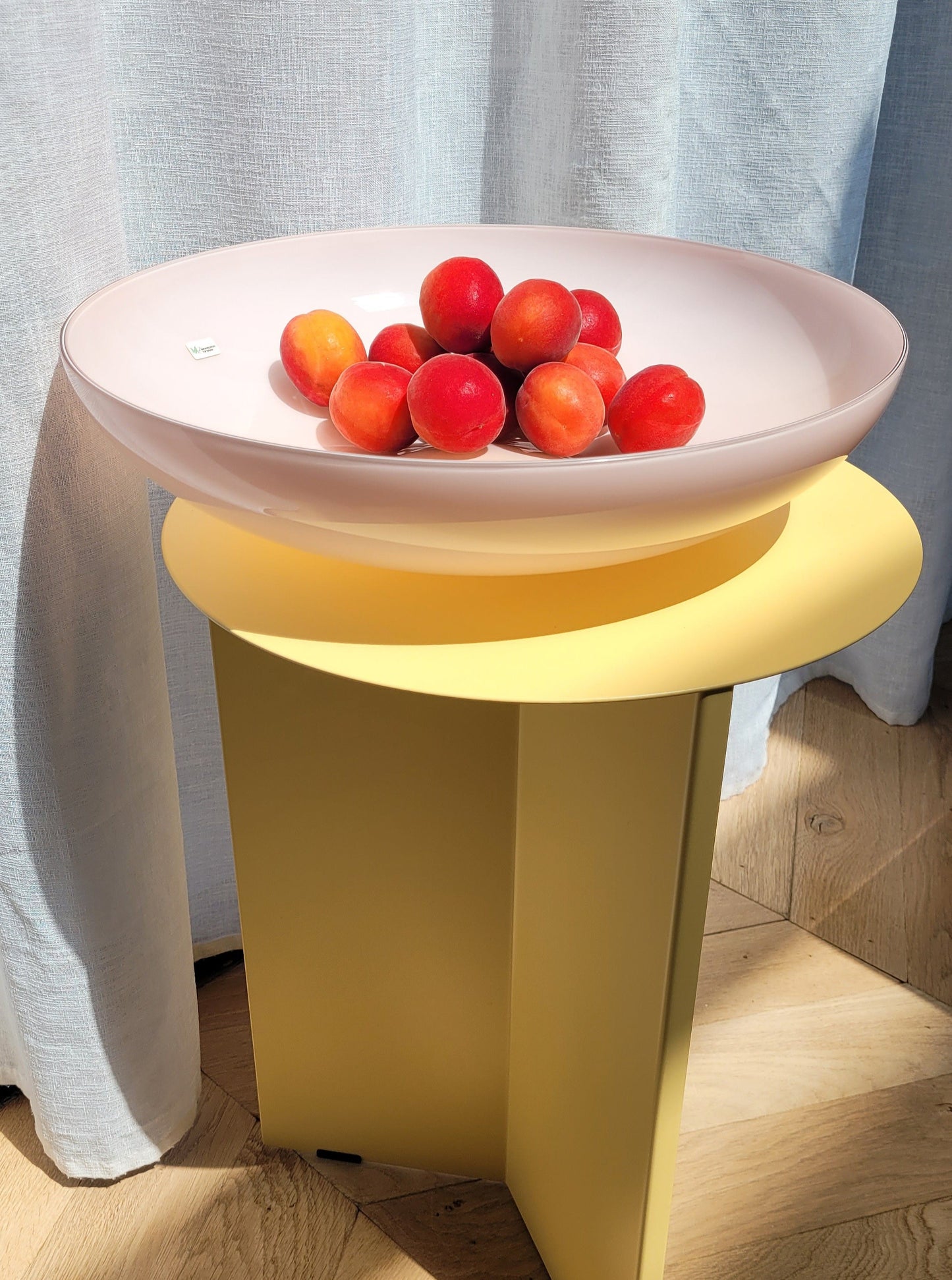full view of a large vintage opal pink Murano bowl filled with fruit on a yellow side table