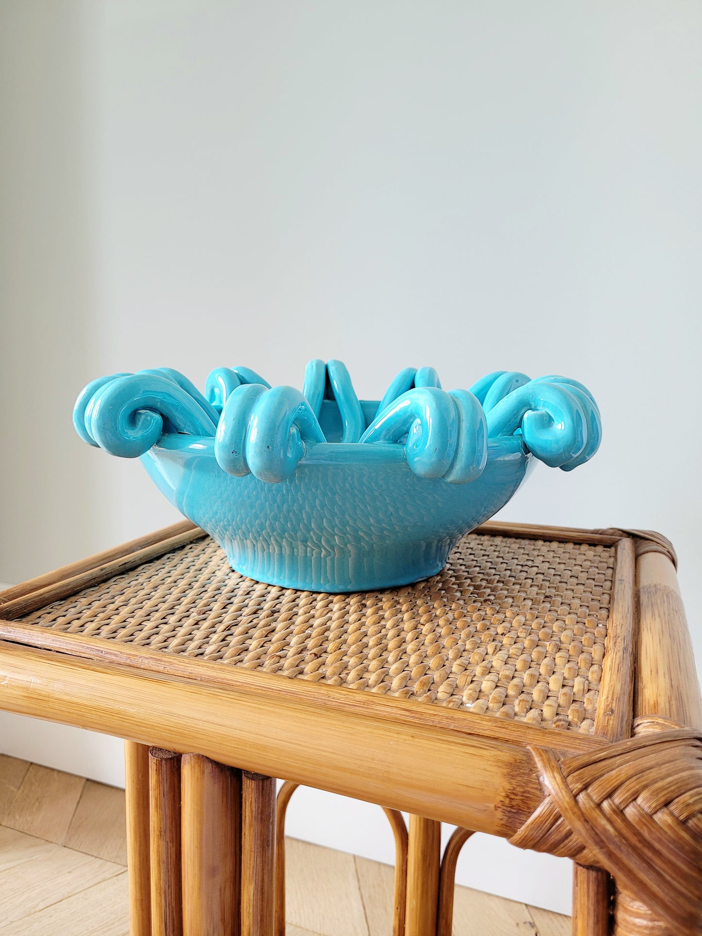 front view of a striking turquoise ceramic serving bowl on a bamboo side table