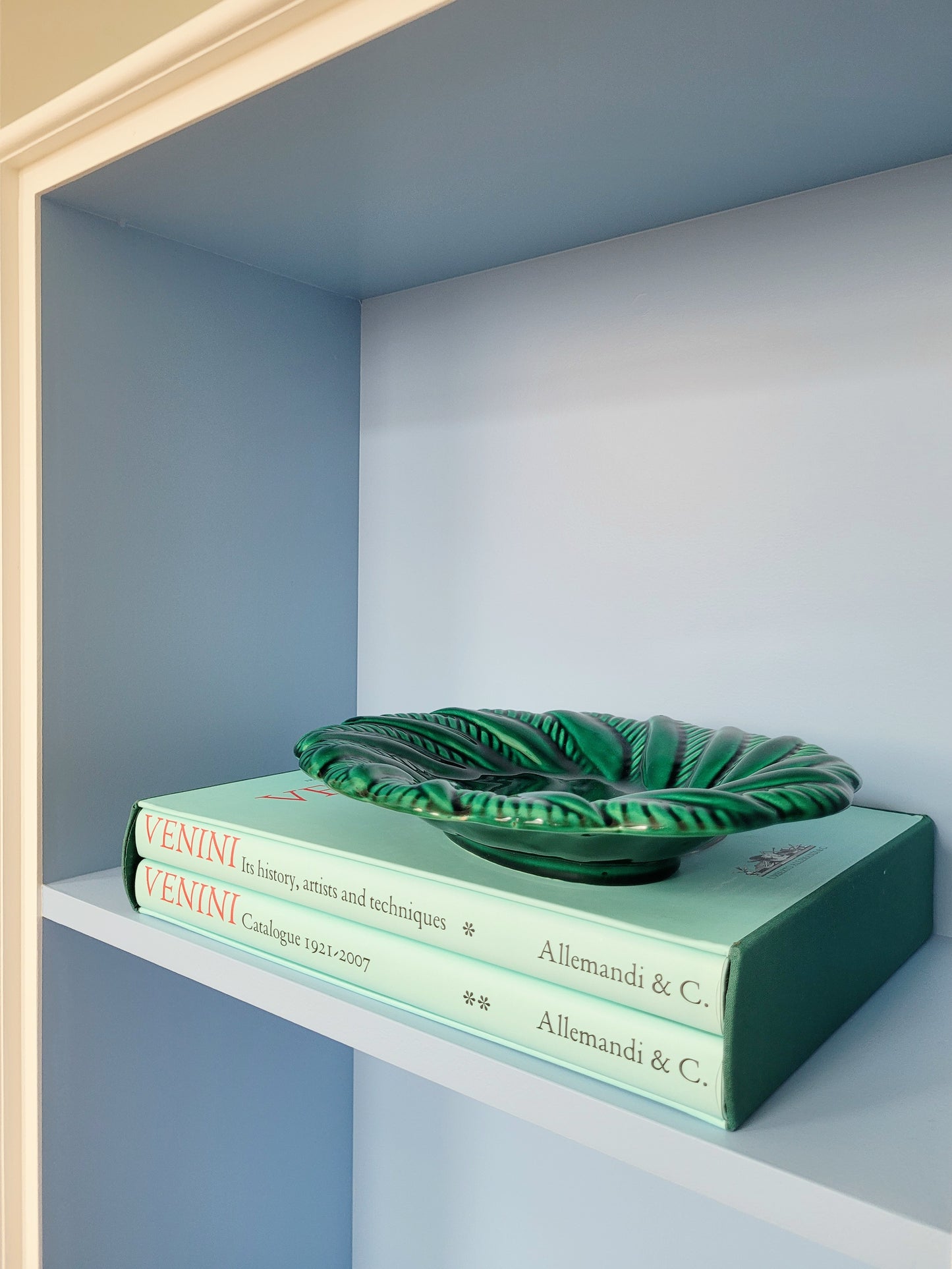 side view of a vintage green ceramic plate on a shelf