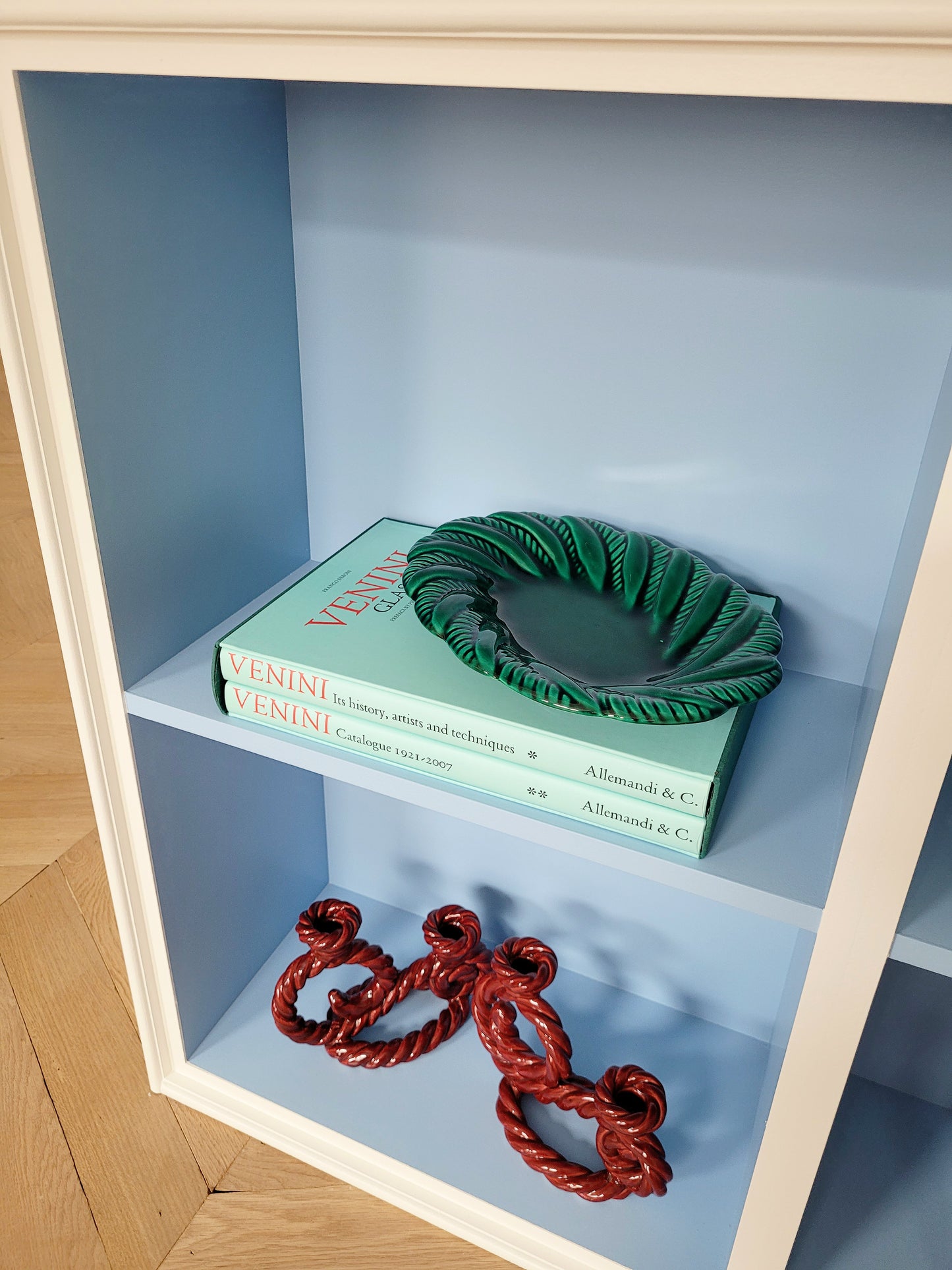 full view of a vintage green ceramic plate on a blue shelf