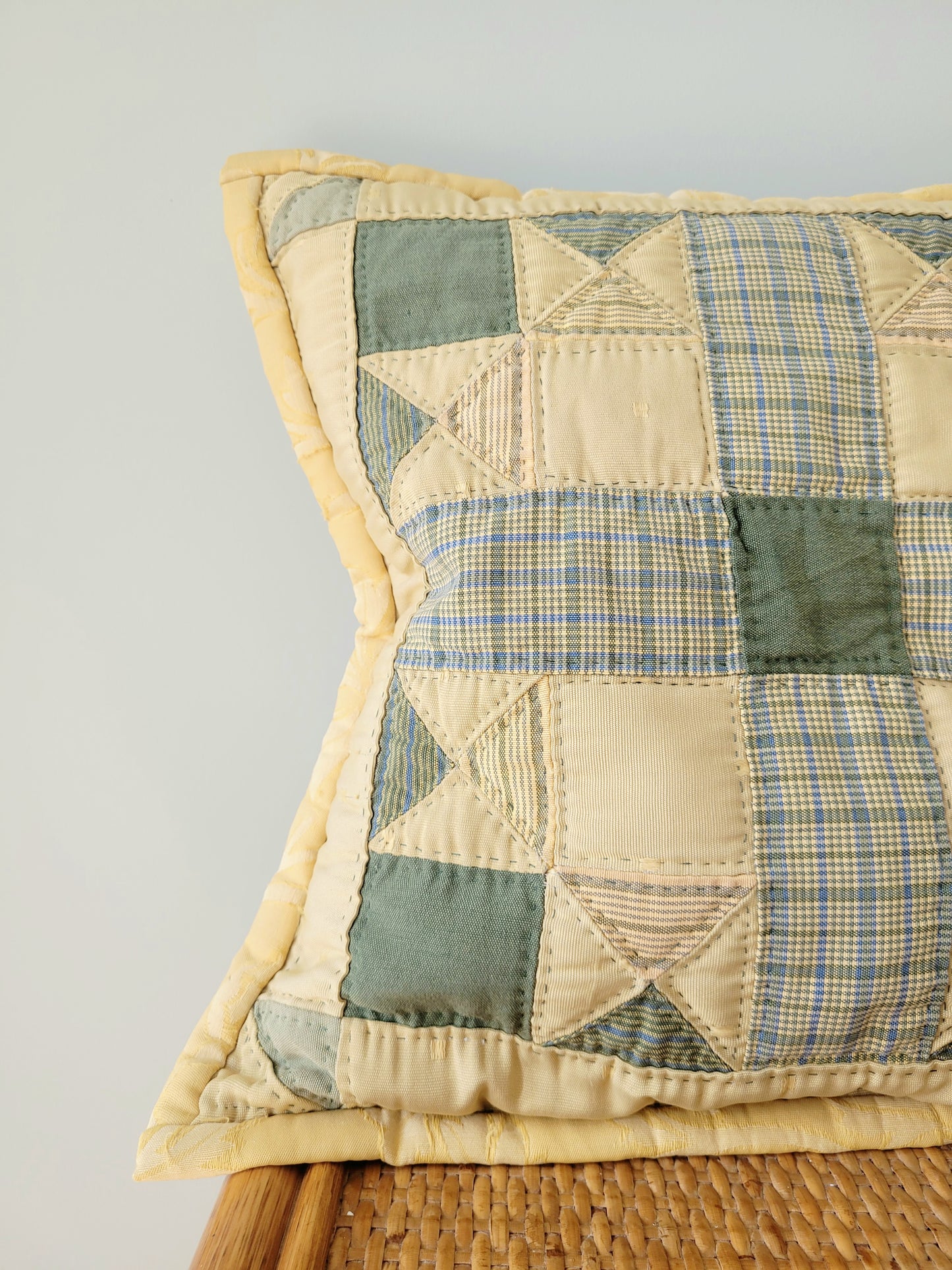 detail of a quilted cushion in green and yellow hues and pattern