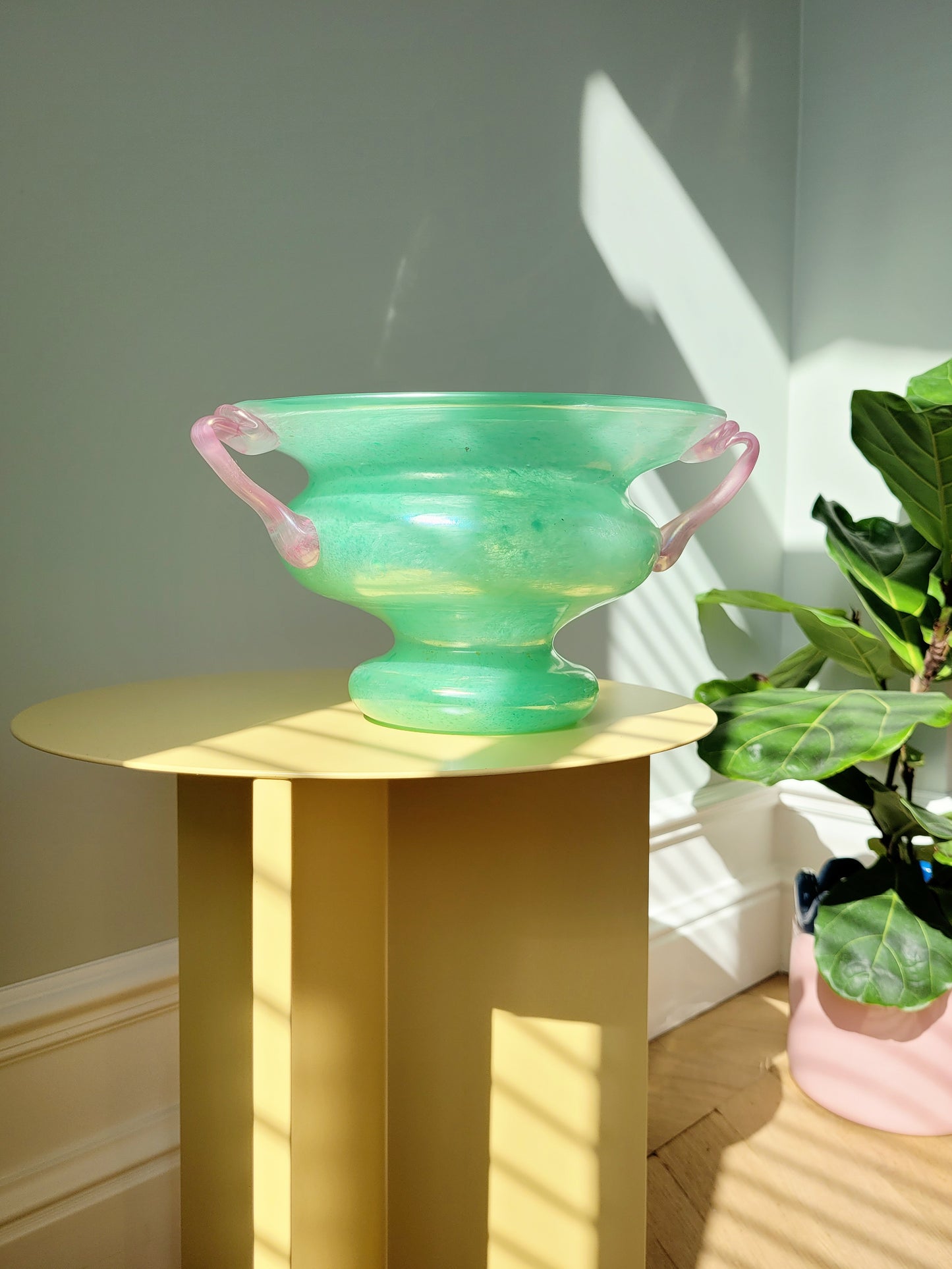 full view of a scavo Murano glass amphora vase in green and pink on a yellow side table