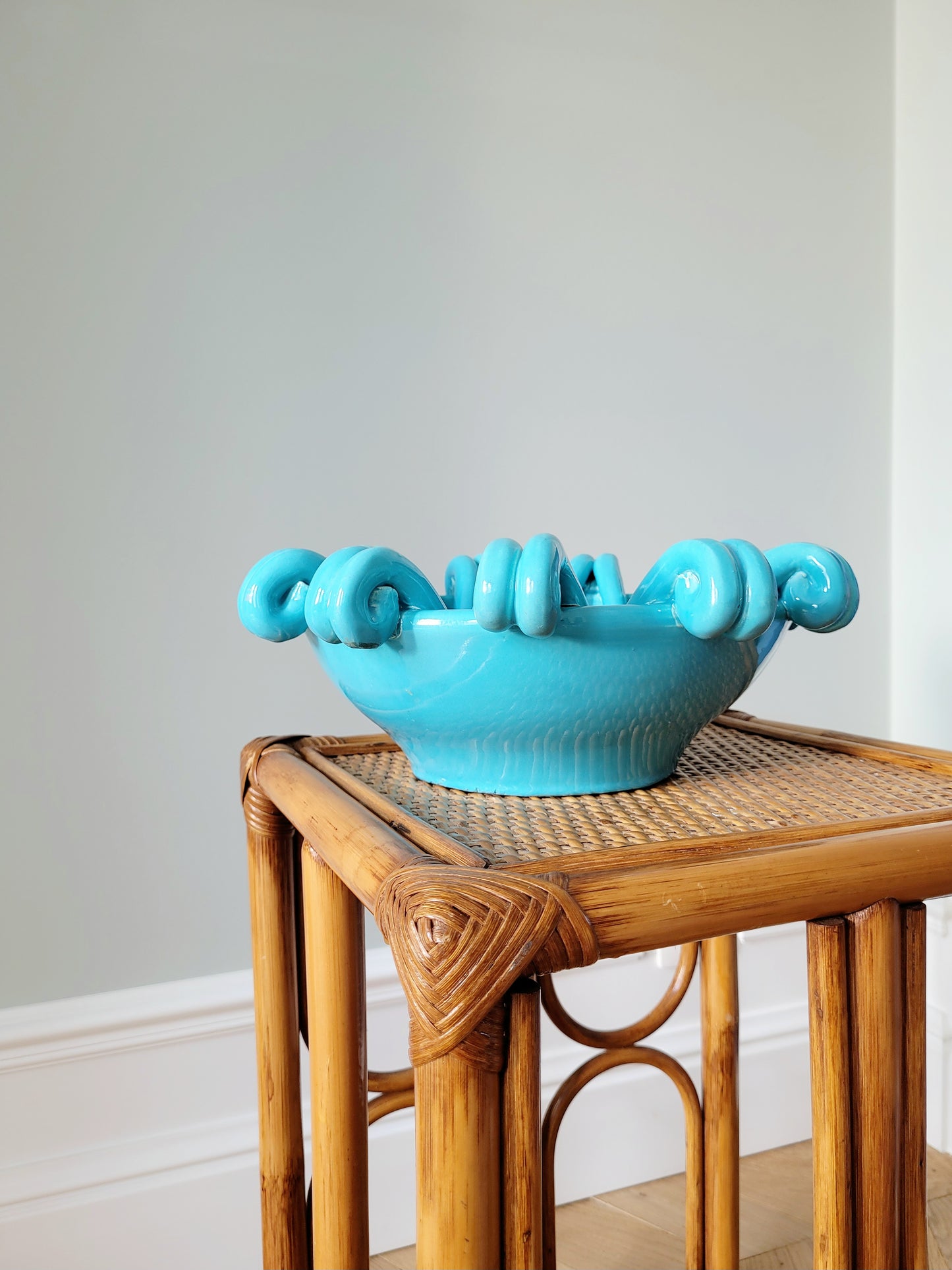 side view of a striking turquoise ceramic serving bowl on a bamboo side table