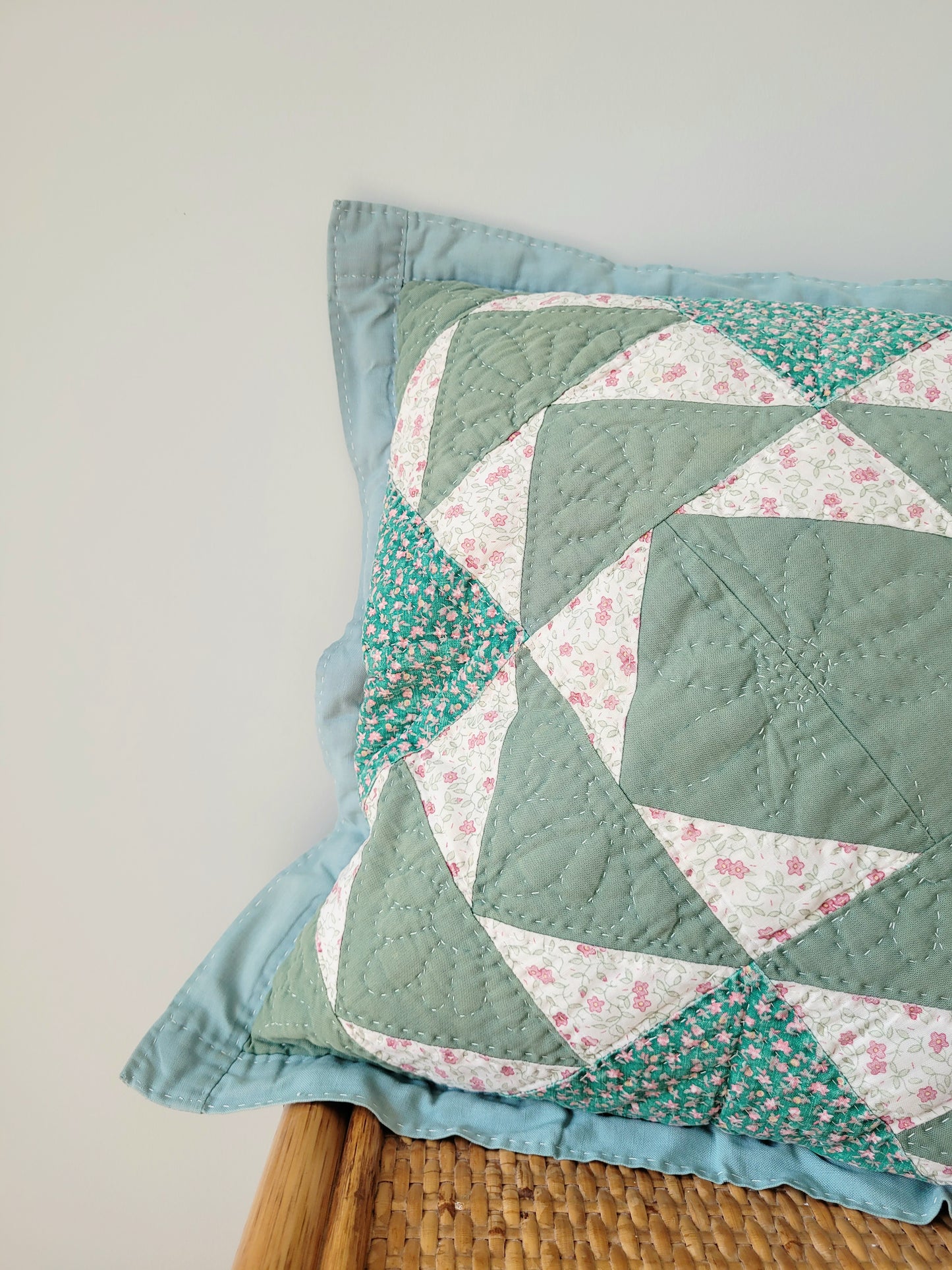 detail of a quilted cushion in green hues and pattern