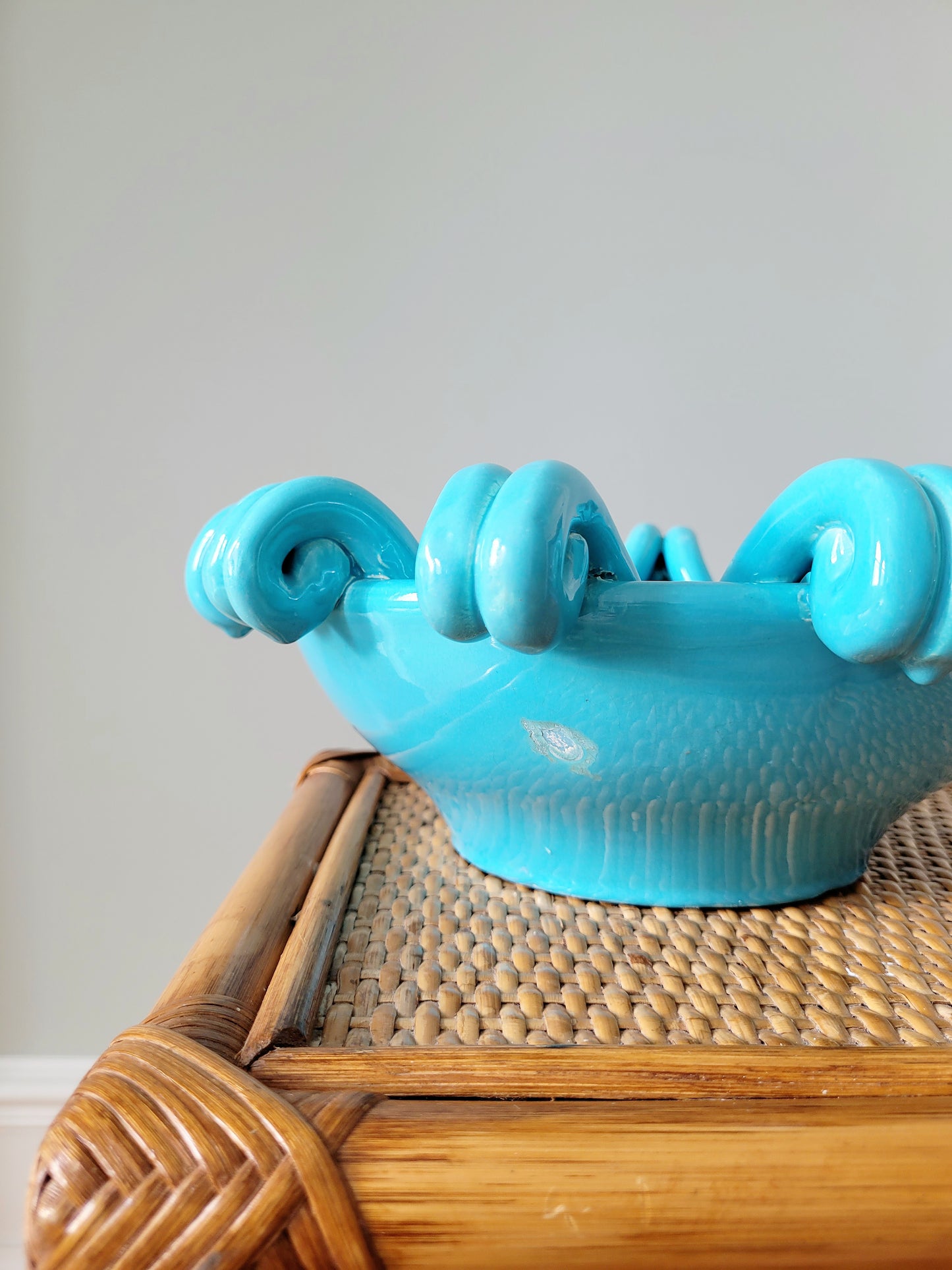detail of a striking turquoise ceramic serving bowl on a bamboo side table