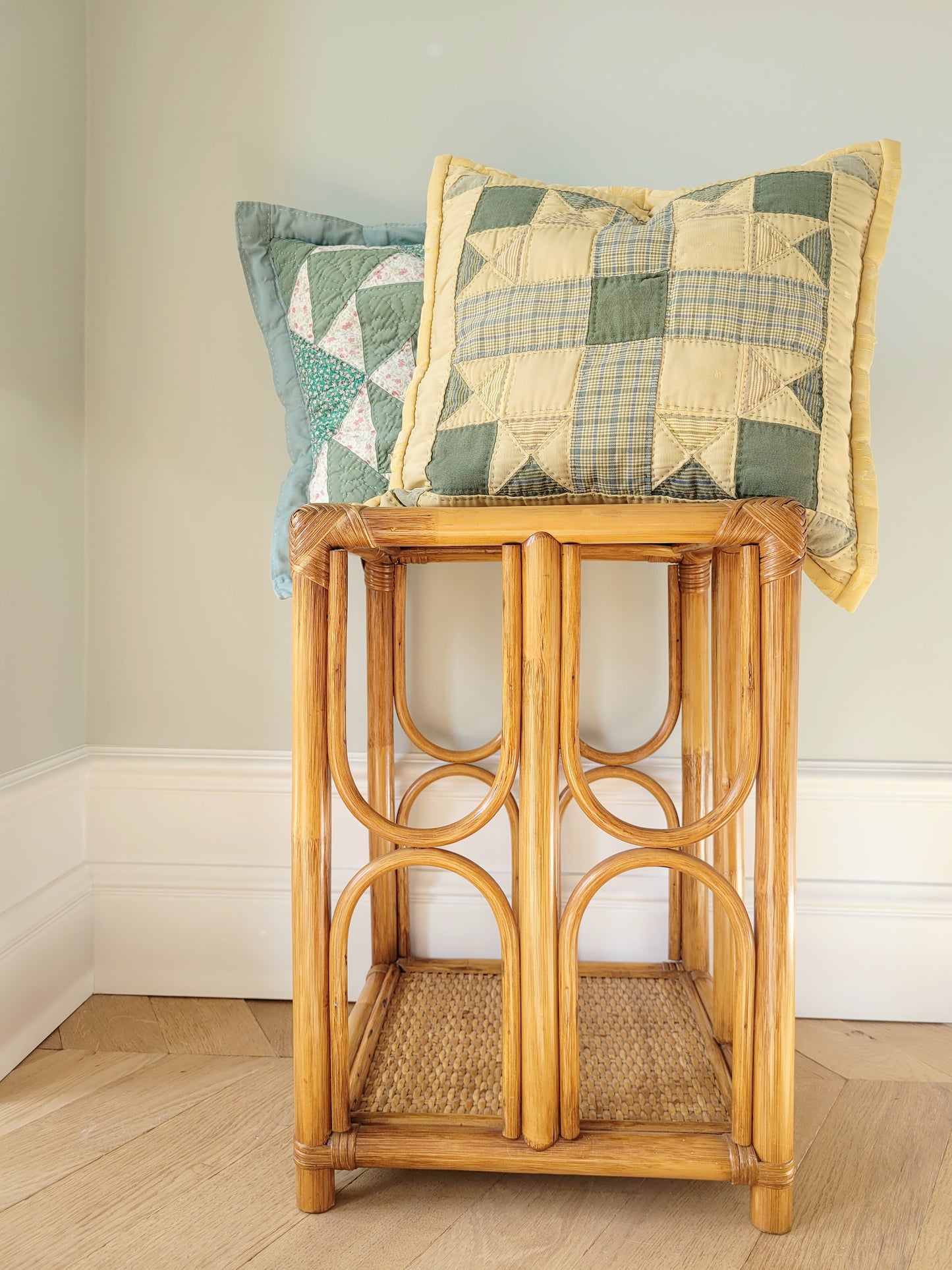 front view of quilted cushions in green and yellow hues and pattern on a bamboo side table