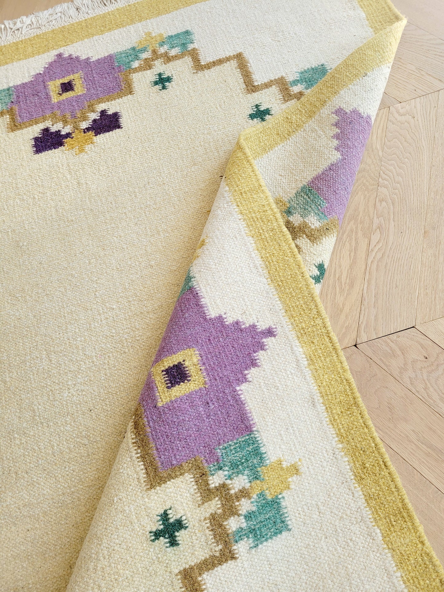 A large flatweave rug in a stunning warm colour palette that incorporates yellow, purple and green