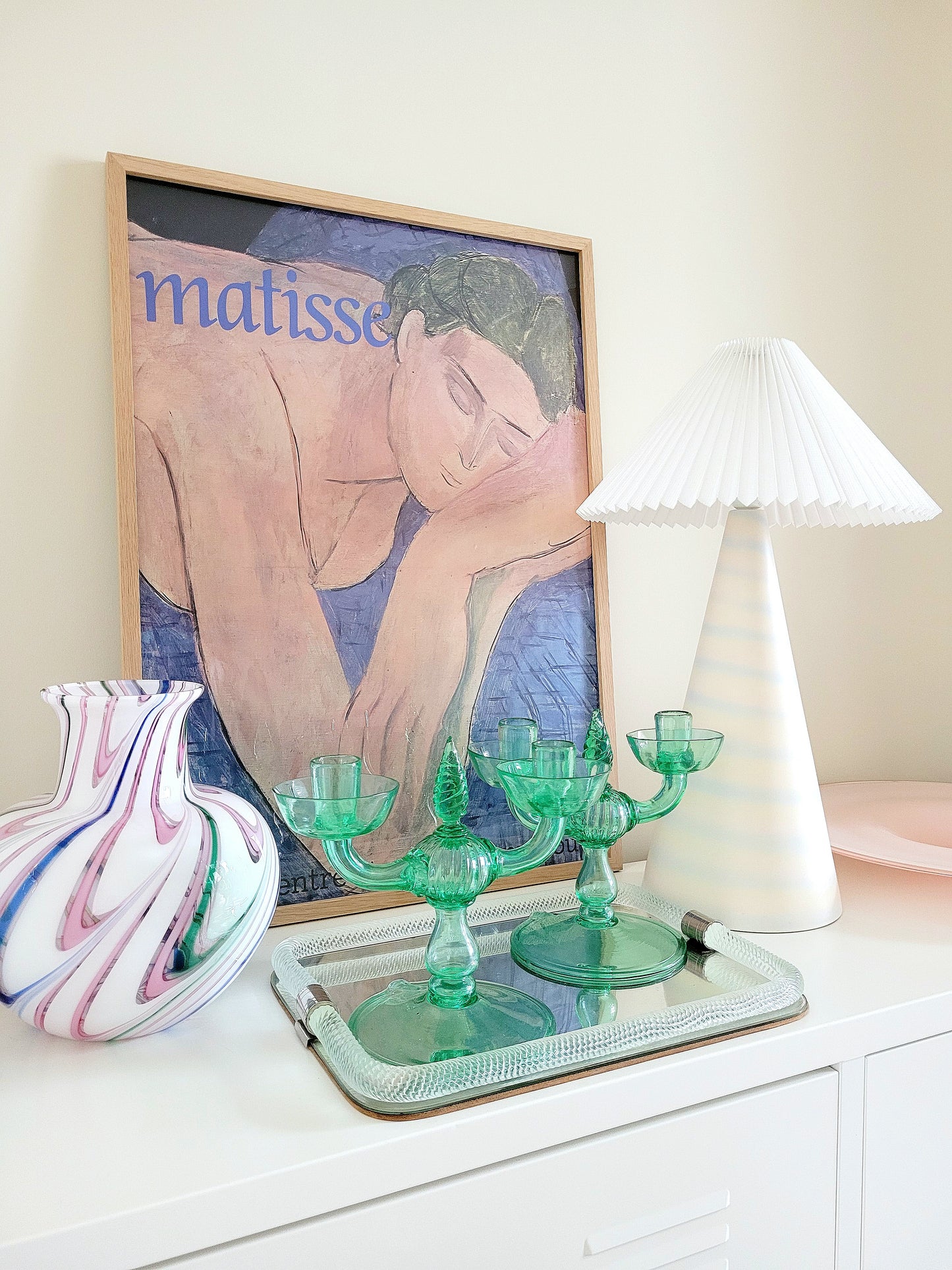 A pair of light green Murano glass candle holders, attributed to Vittorio Zecchin, renowned Italian artist on a vintage Murano mirror tray and with a Murano vase in the back and a framed Matisse poster.