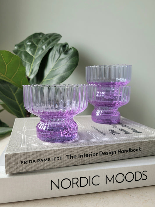 front view of three purple Italian glasses and cups on a stack of interior books