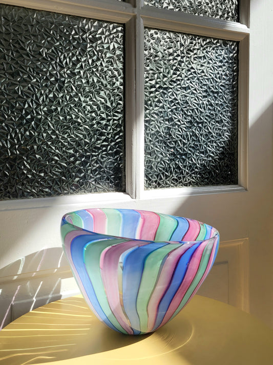 front view of a vintage candy stripe Murano bowl on a yellow side table