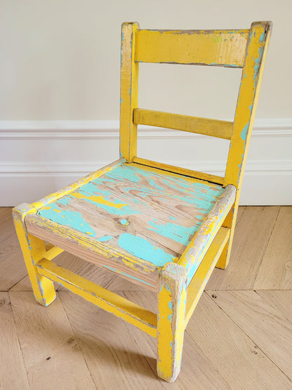 side view of a characterful wooden kids chair in yellow and green with patina
