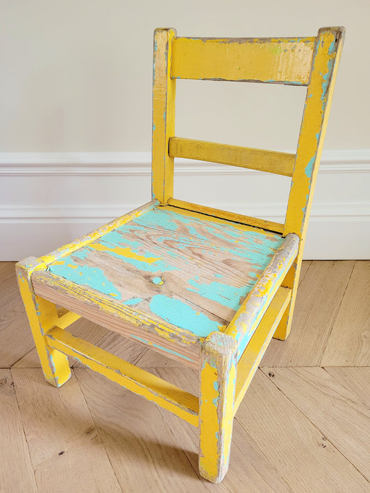 side view of a characterful wooden kids chair in yellow and green with patina