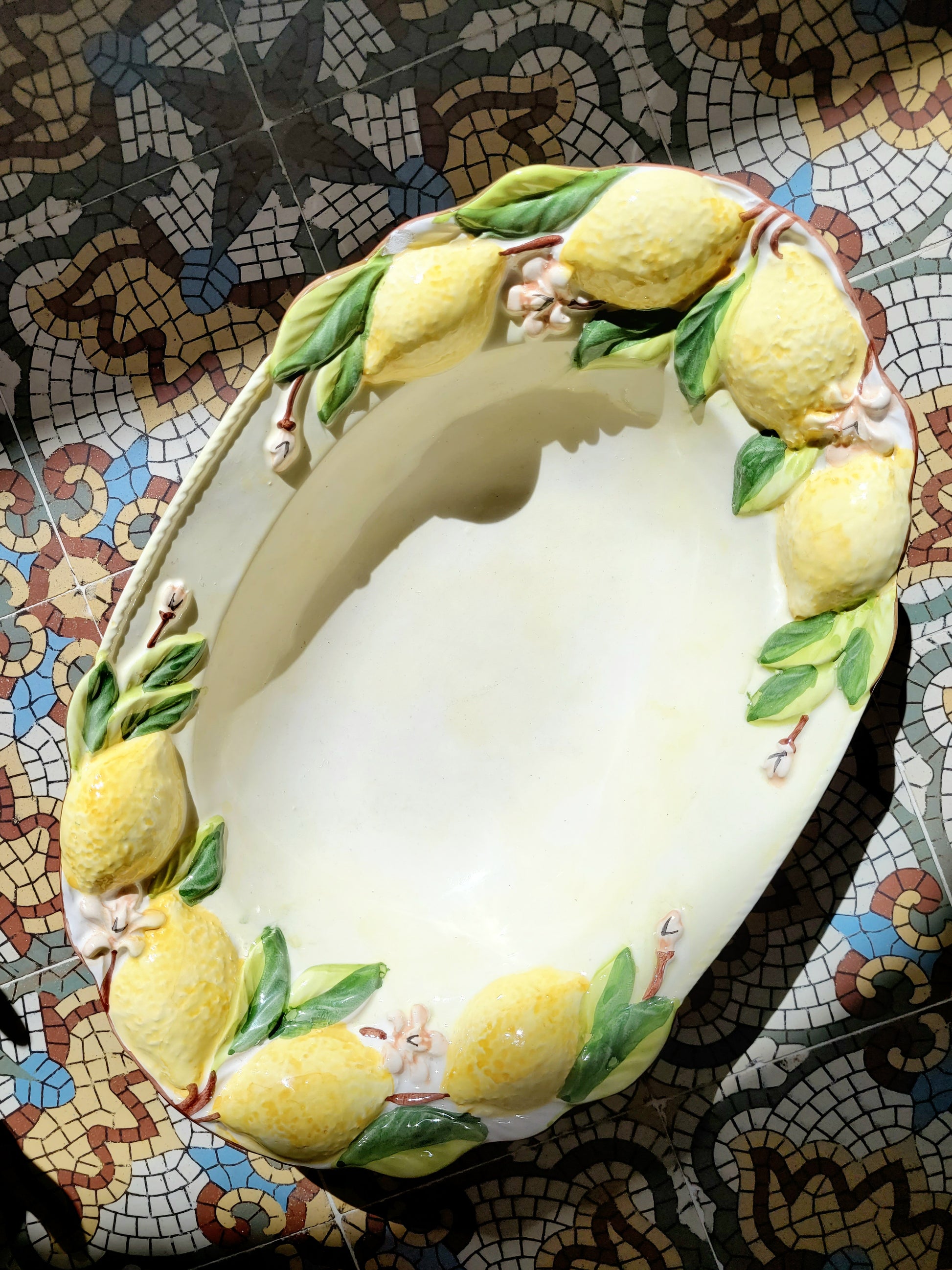 full top view of a deep ceramic oval dish with lemons in relief