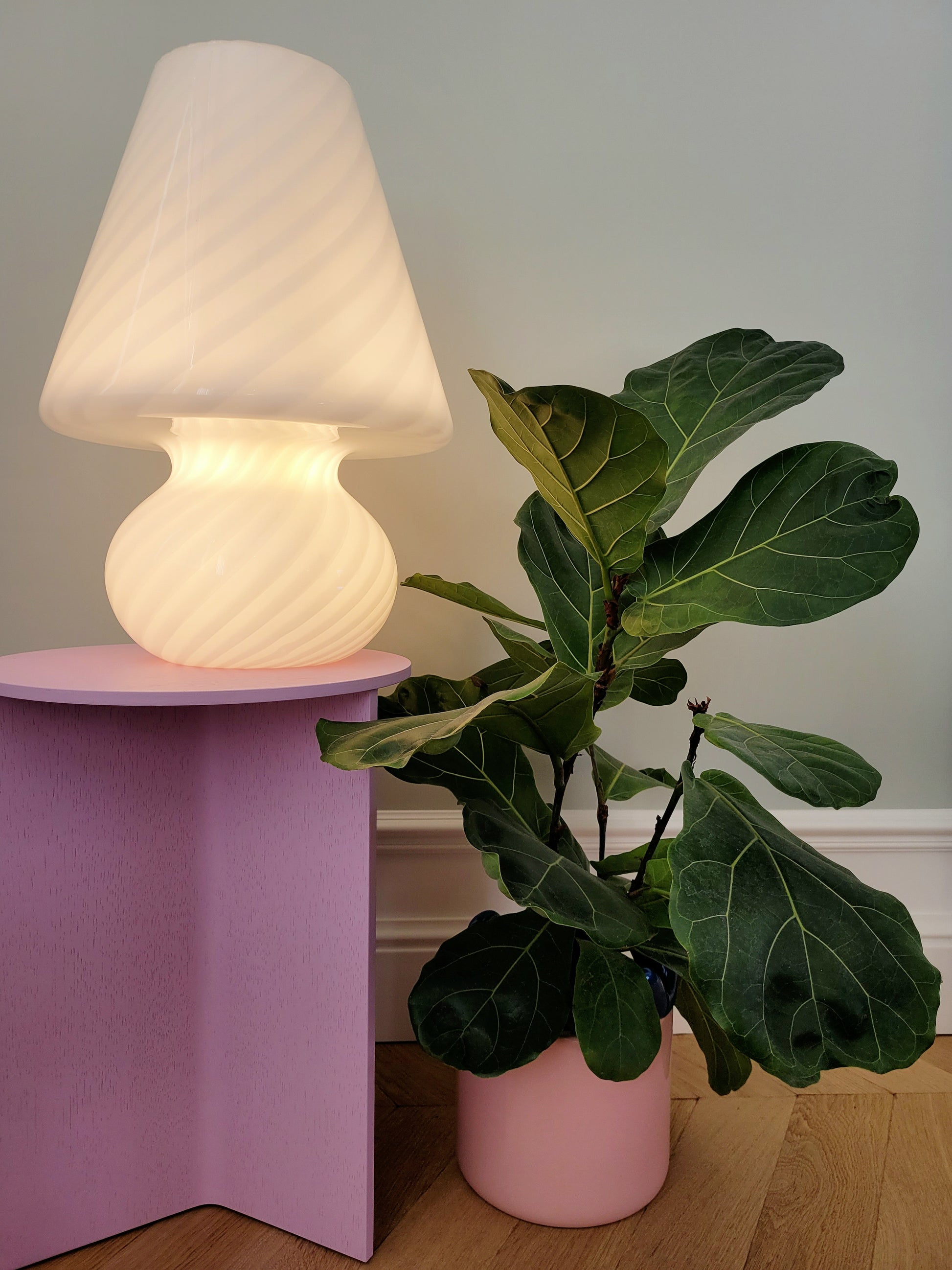 full view of an extra large vintage Murano white swirl mushroom lamp illuminated on a purple side table