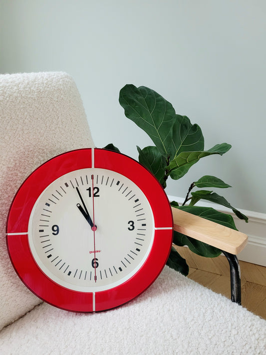 front view of a Guzzini acrylic red wall clock on an armchair