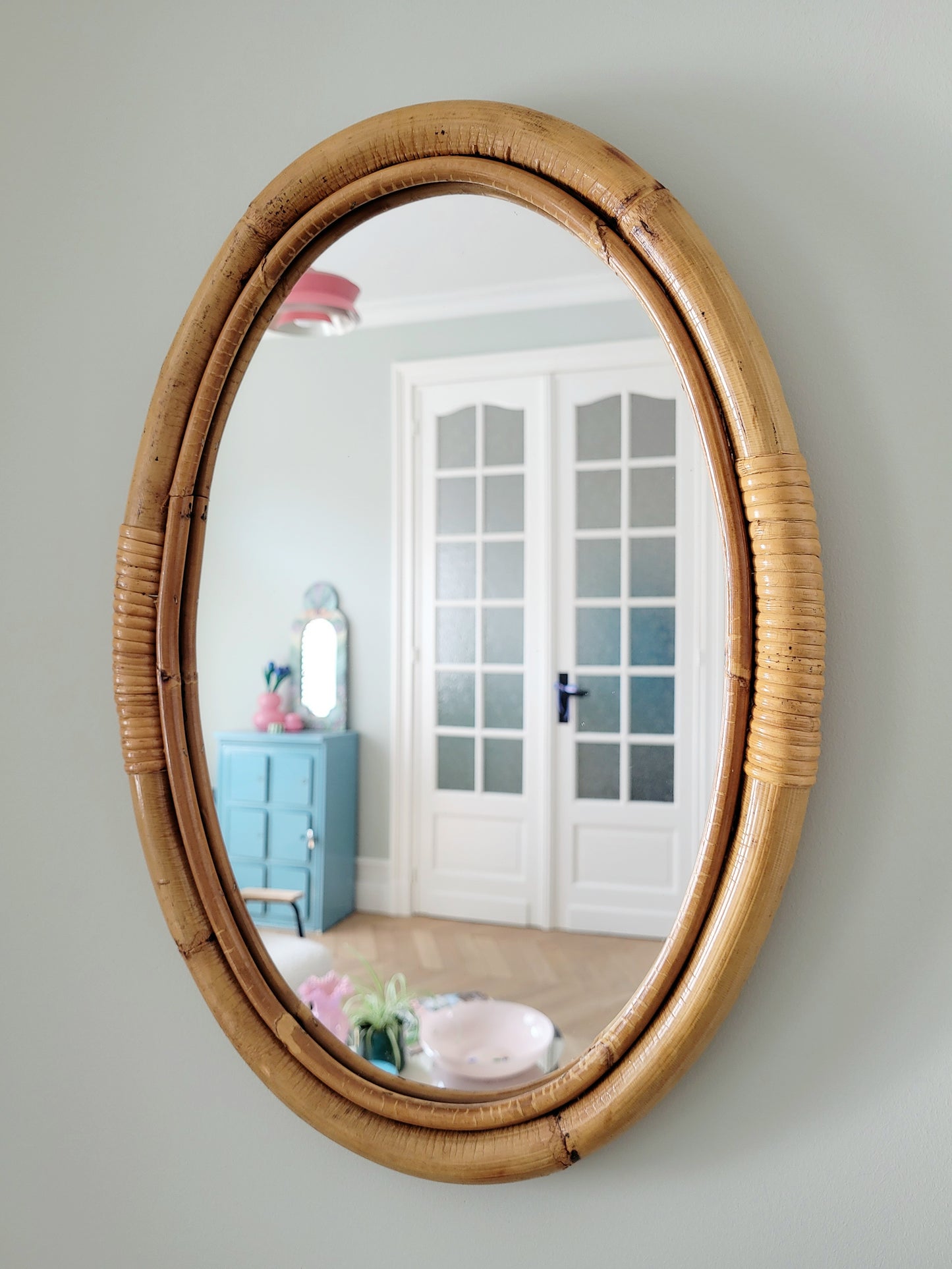 full view of an oval wall mirror in natural bamboo