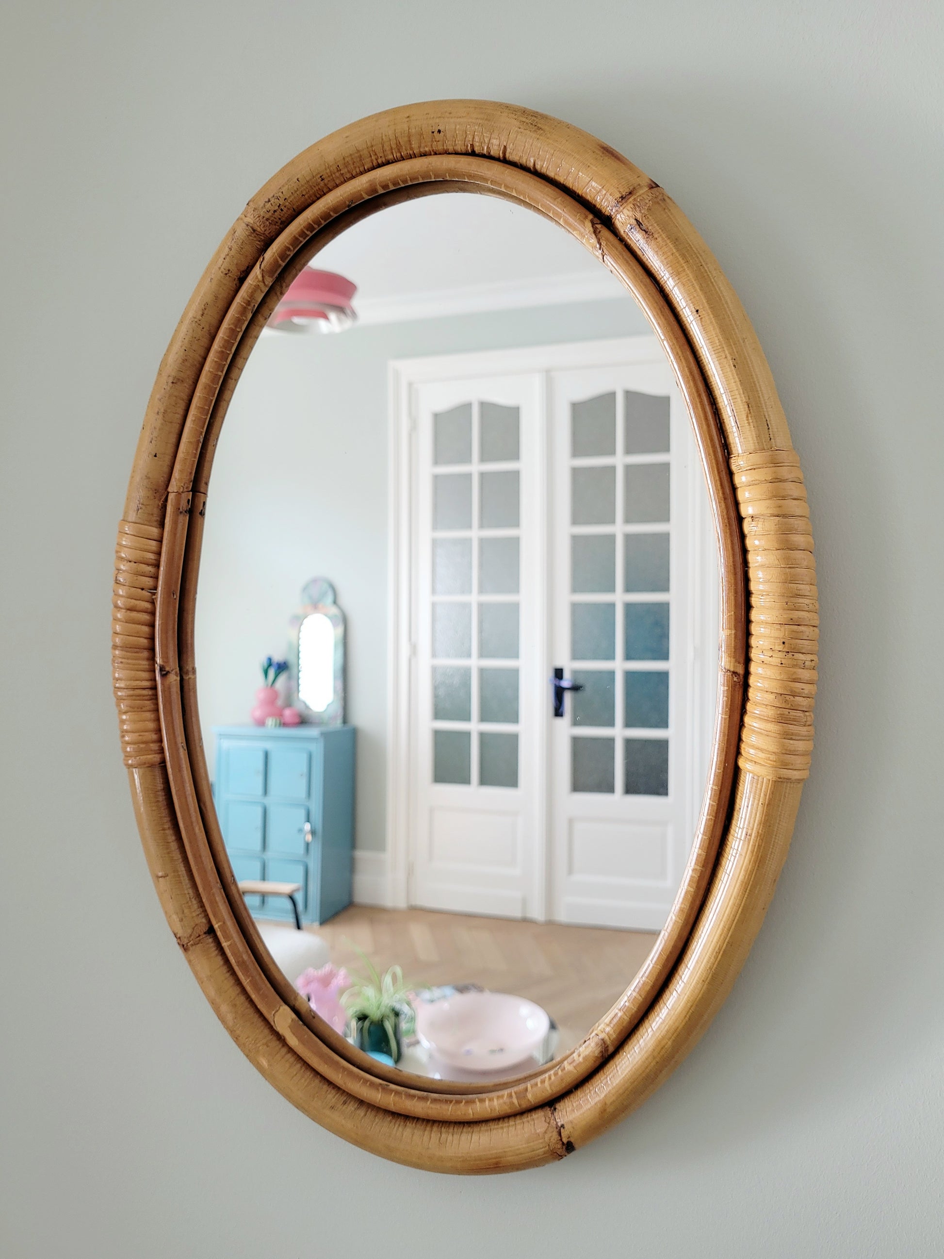 full view of an oval wall mirror in natural bamboo