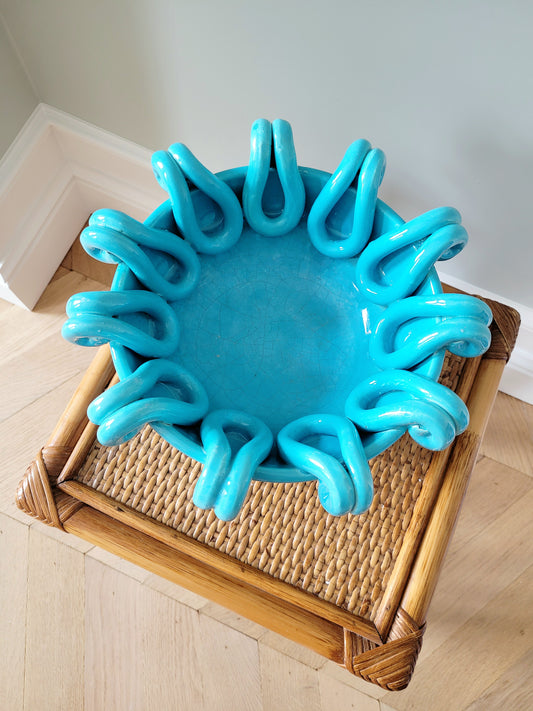 top view of a striking turquoise ceramic serving bowl on a bamboo side table